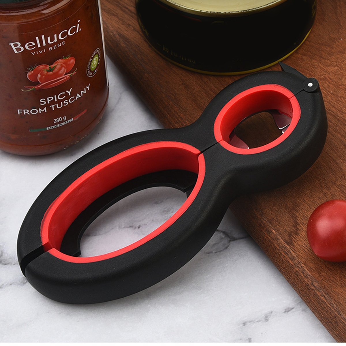 Ein schwarzer und roter Dosenöffner liegt neben einem Glas Tomatensoße.