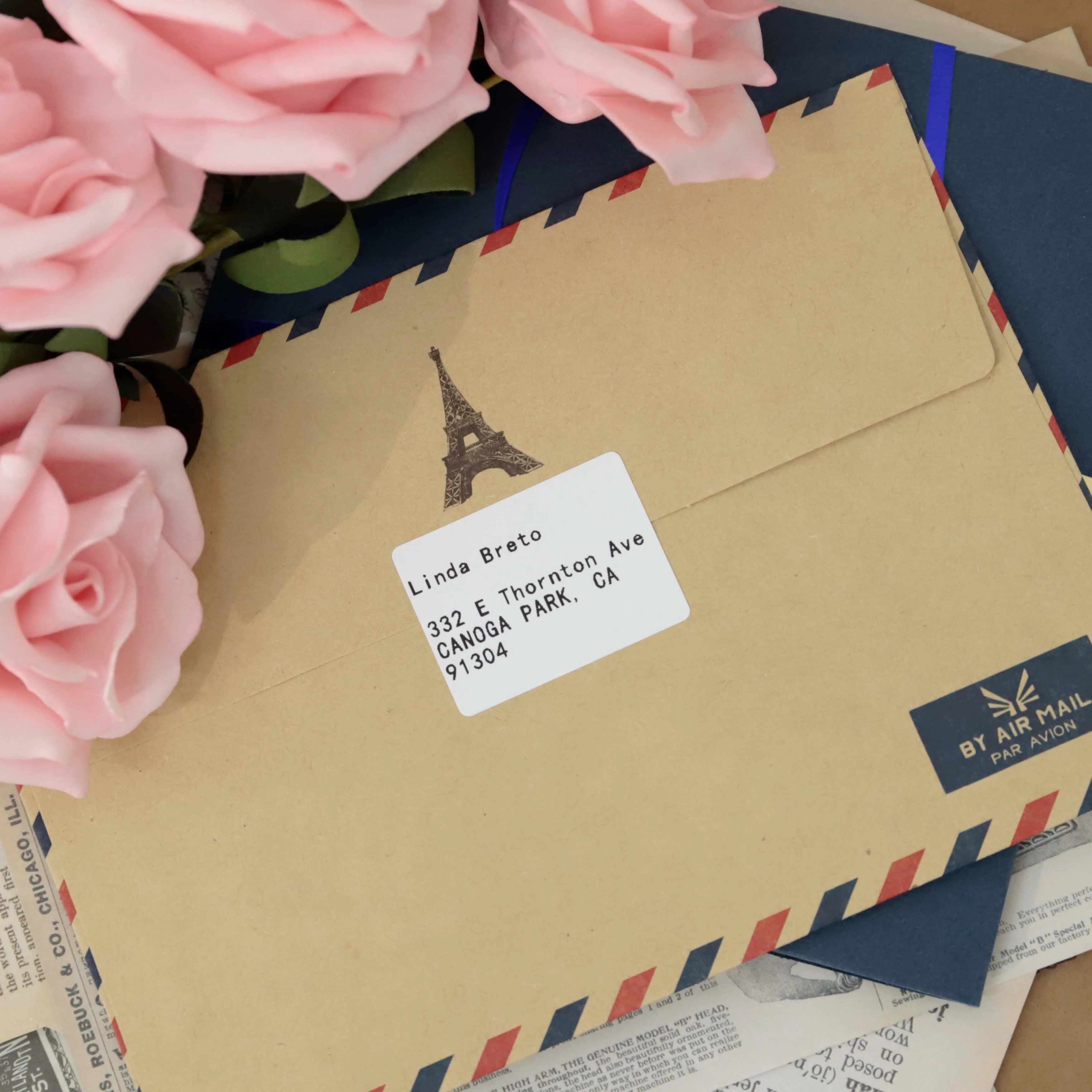 Buste marroni per posta aerea con fiori, etichetta indirizzo e timbro Torre Eiffel.