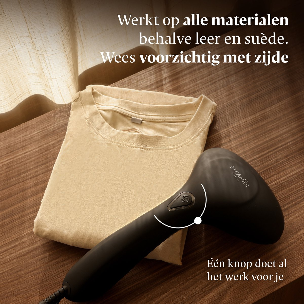 Een kledingstomer ligt naast een lichtbeige t-shirt op een houten ondergrond.