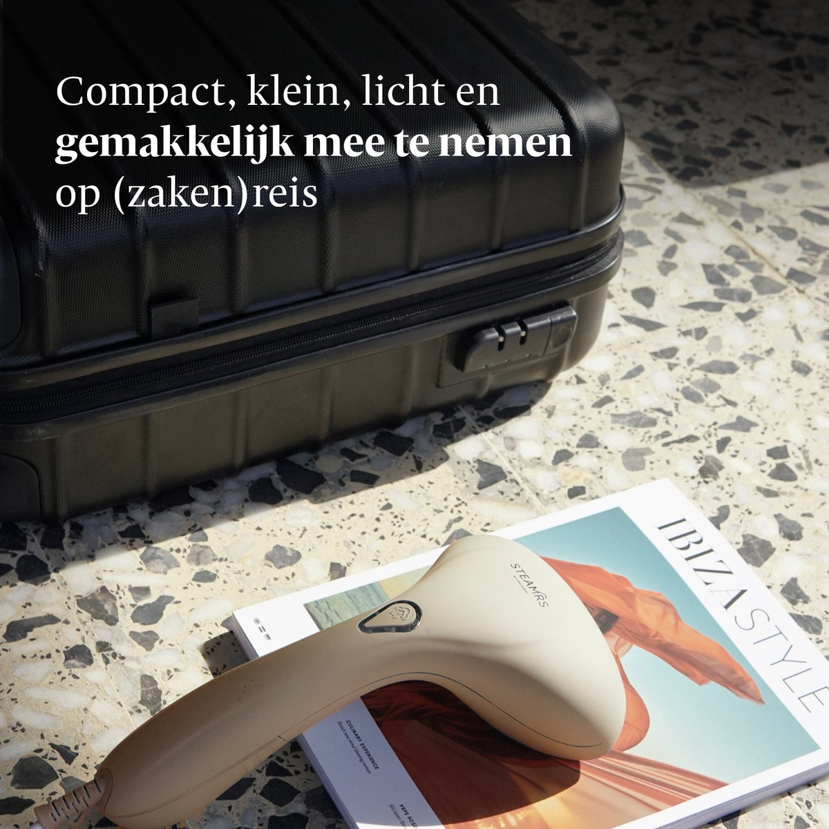 Een zwarte koffer en handstomer liggen op een stenen vloer.