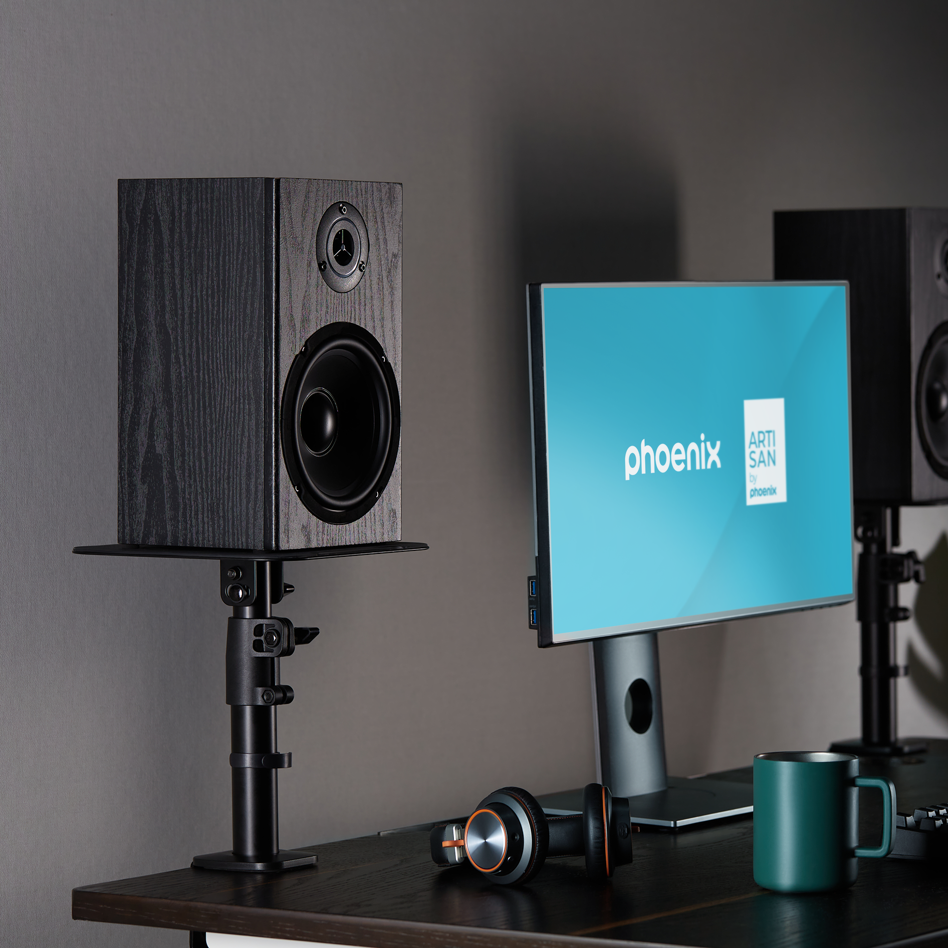 Un altavoz negro está en un soporte junto a un monitor con pantalla azul.