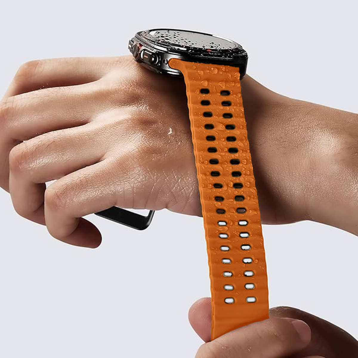 Eine Orange Smartwatch mit einem Armband, bedeckt mit Wassertropfen, an einem Handgelenk.