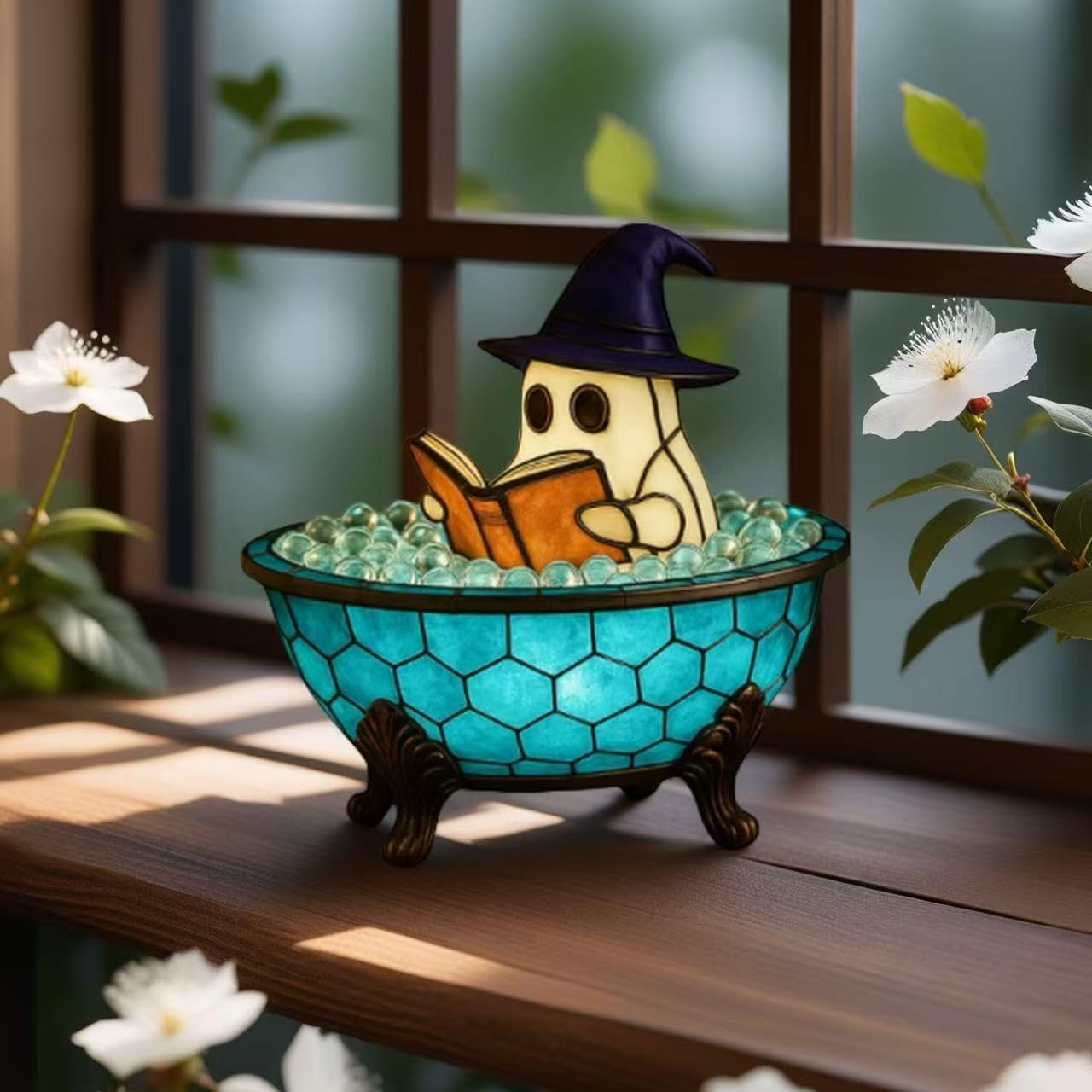Un fantasma con cappello legge un libro in una ciotola blu piena di sfere di vetro.