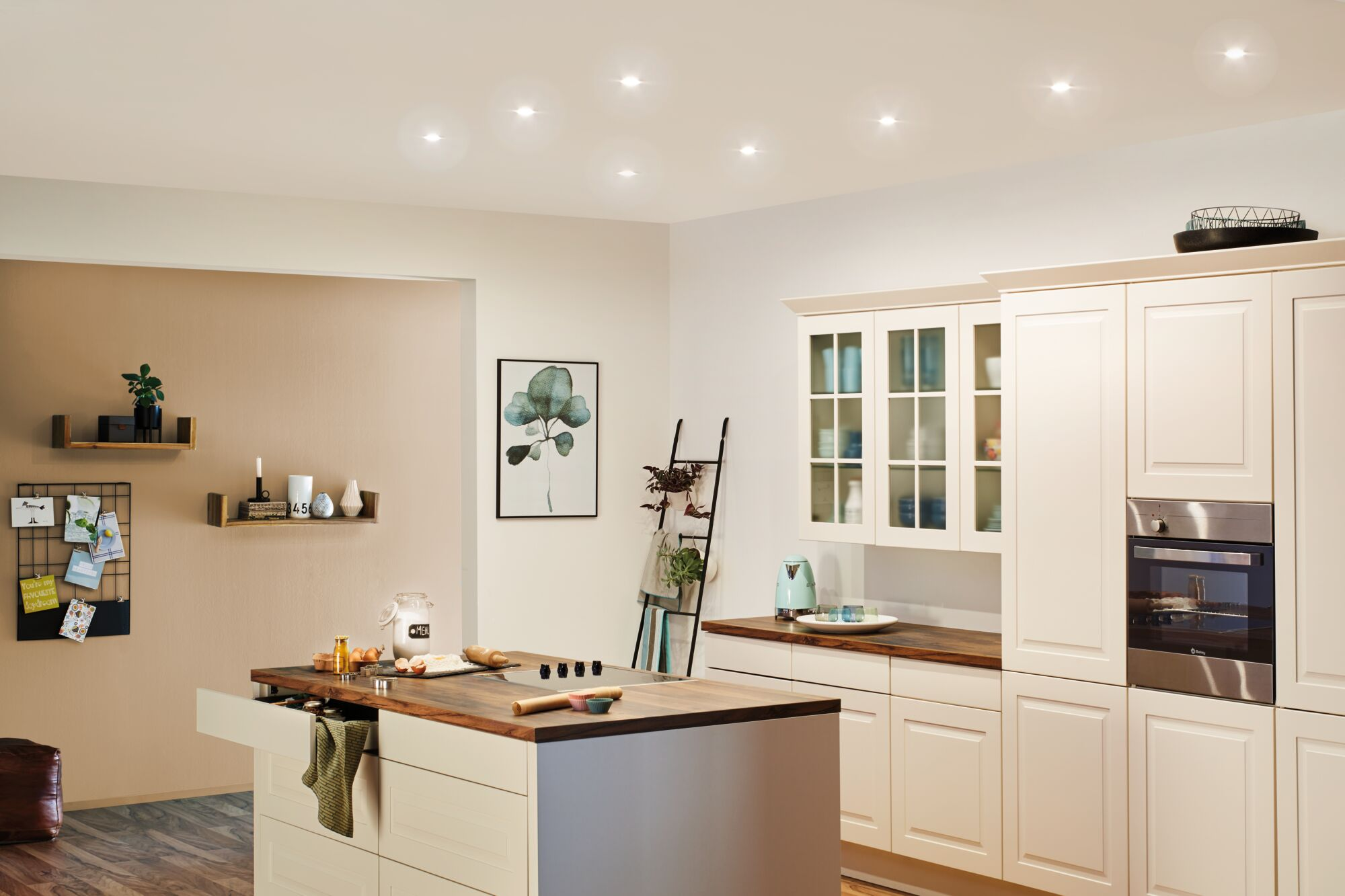 Jasna kuchnia z wyspą, szafkami, piekarnikiem, obrazem i drabiną.