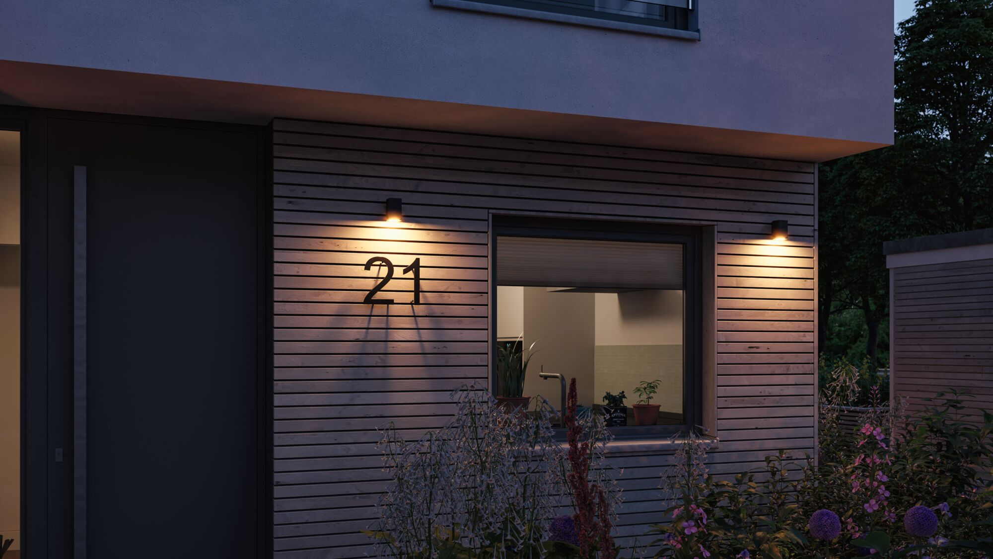 Hausfassade mit Holzverkleidung, Fenster, Tür und Hausnummer 21.