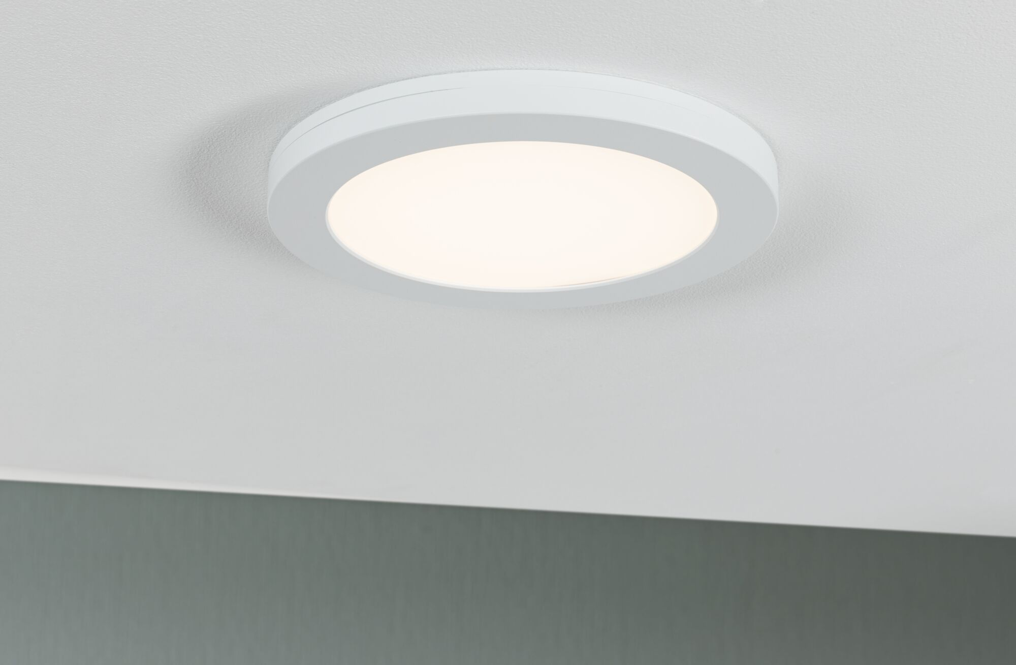 Eine weiße Deckenleuchte mit hellem Licht leuchtet auf einer weißen Decke.