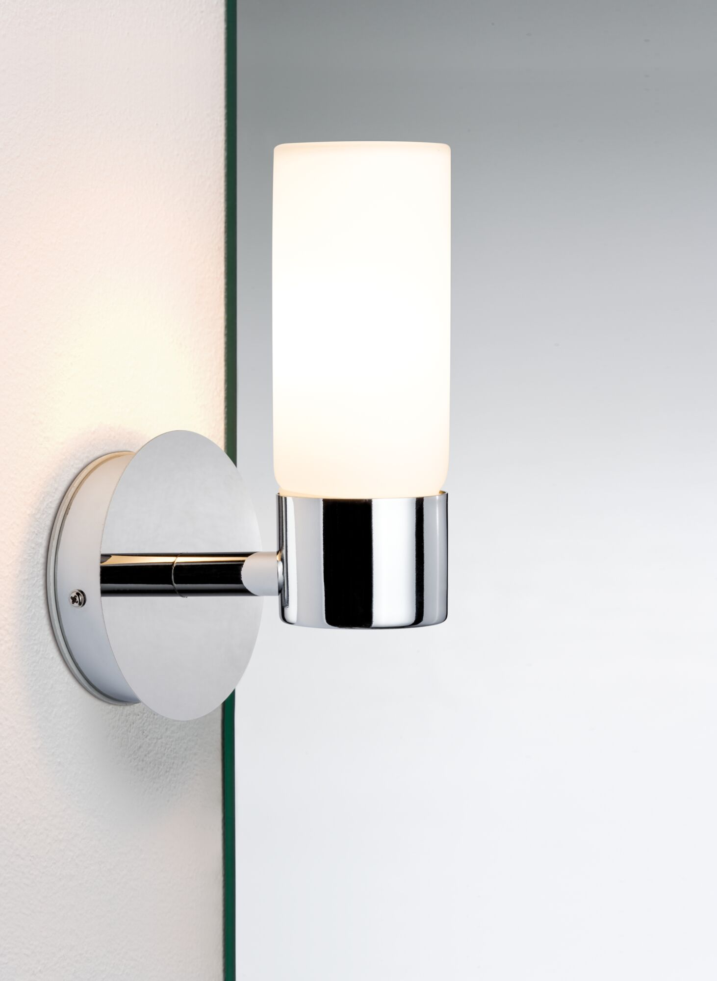 Une applique murale moderne avec abat-jour cylindrique en verre dépoli et base chromée.