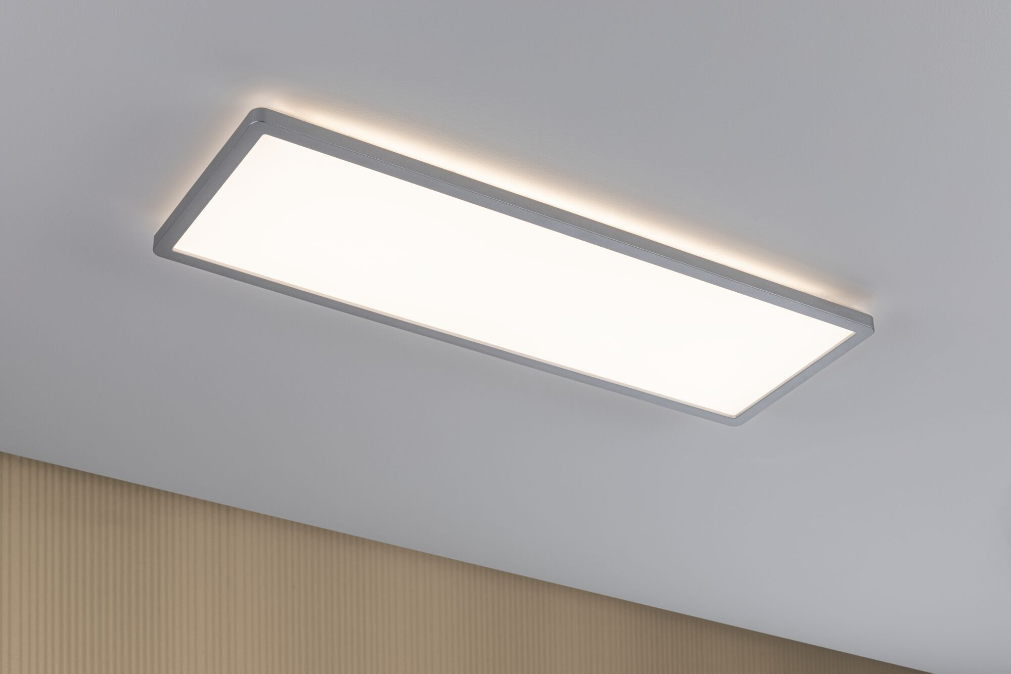 Una plafoniera rettangolare con cornice grigia brilla intensamente su un soffitto bianco.