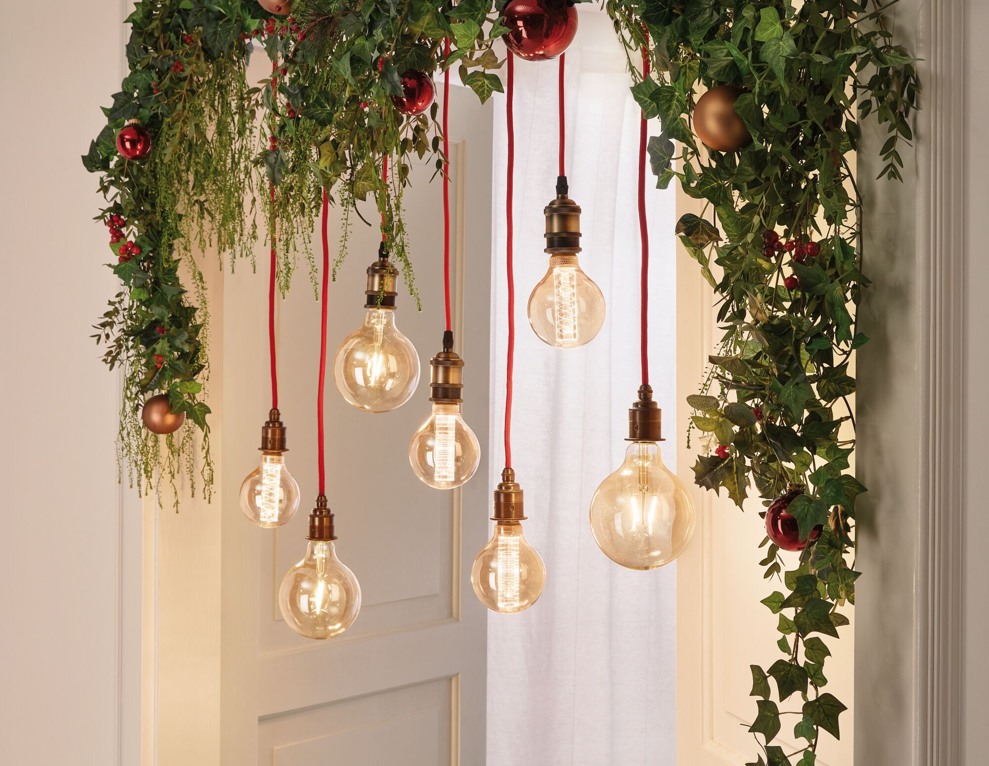 Girlanda z liśćmi bluszczu, czerwonymi jagodami i żarówkami.