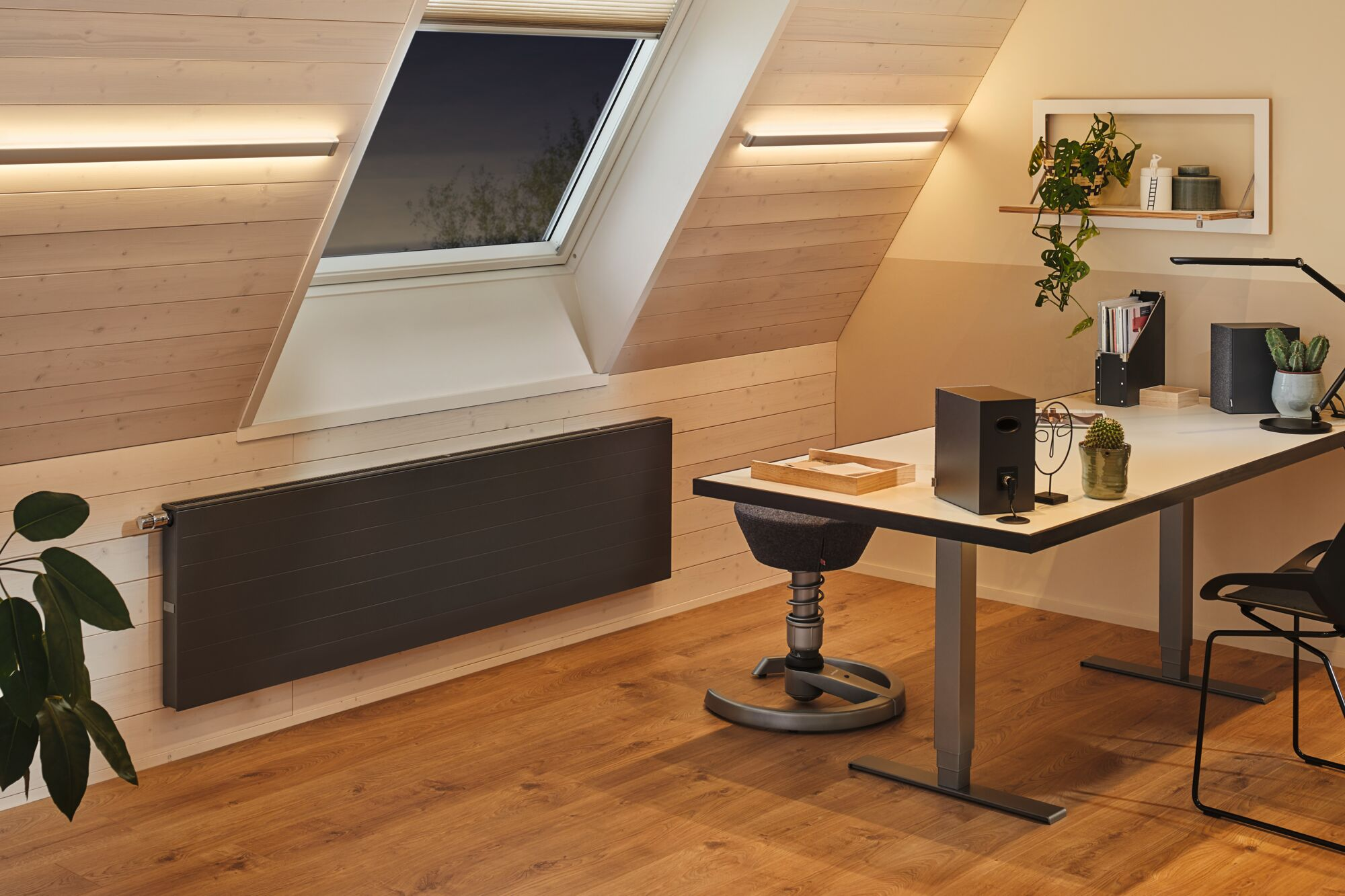 Nowoczesne miejsce pracy pod świetlikiem z ciemnym grzejnikiem.