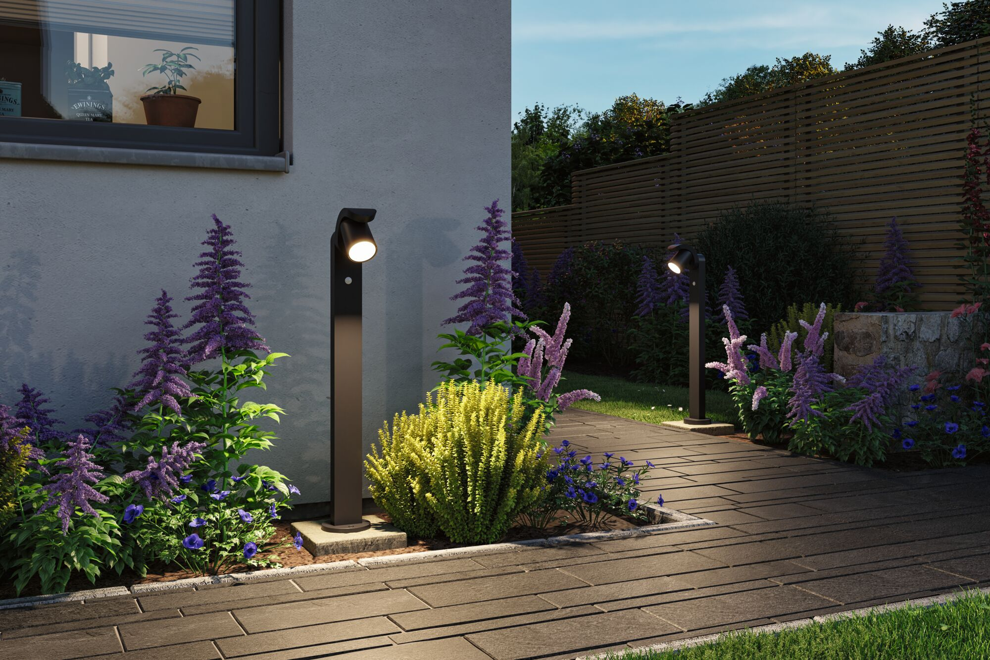 Ścieżka w ogrodzie z nowoczesnymi lampami i fioletowymi i żółtymi kwiatami.