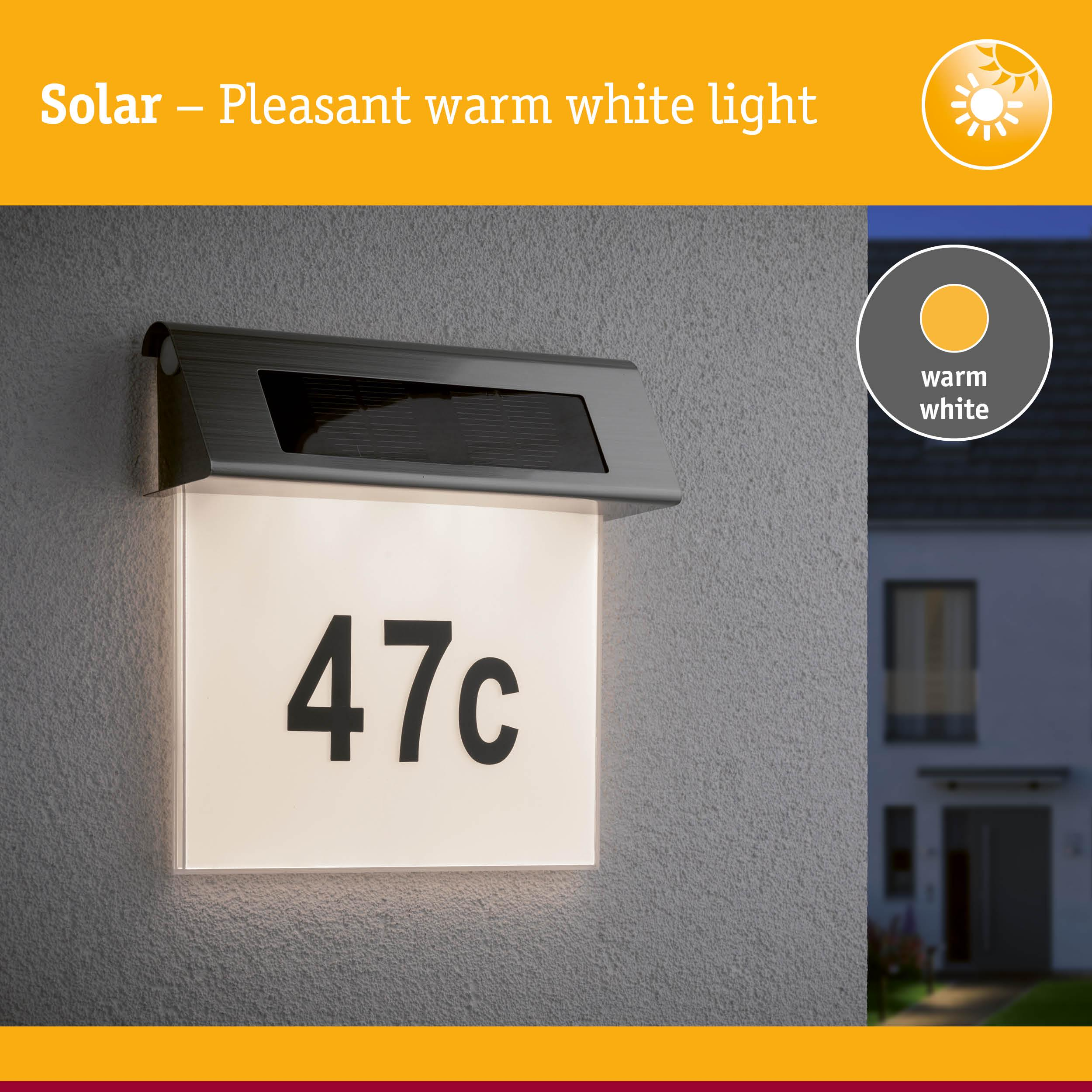 Luce solare per numero civico "47c" su un muro, con una casa sullo sfondo.