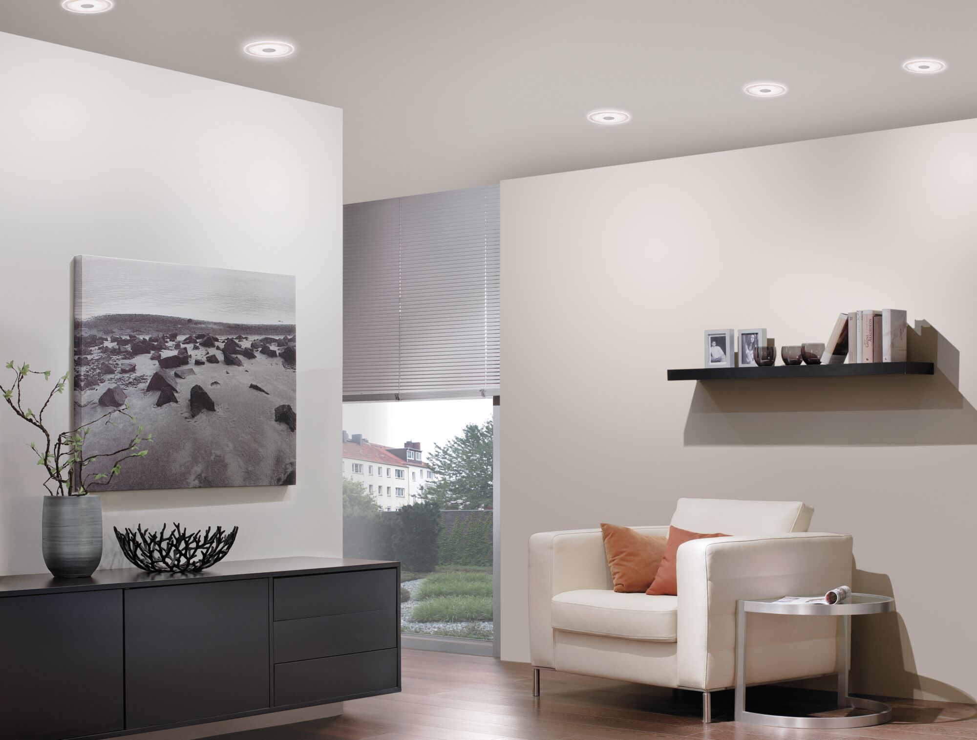 Un soggiorno luminoso con divano bianco, tavolino e credenza nera.