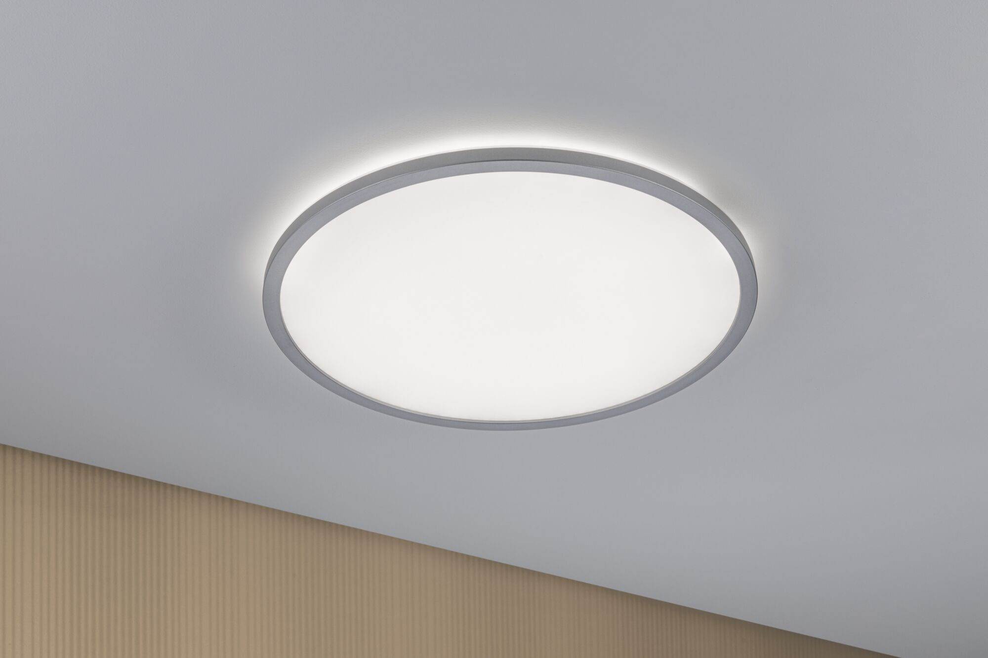 Una lampada da soffitto rotonda con bordo grigio illumina una stanza.