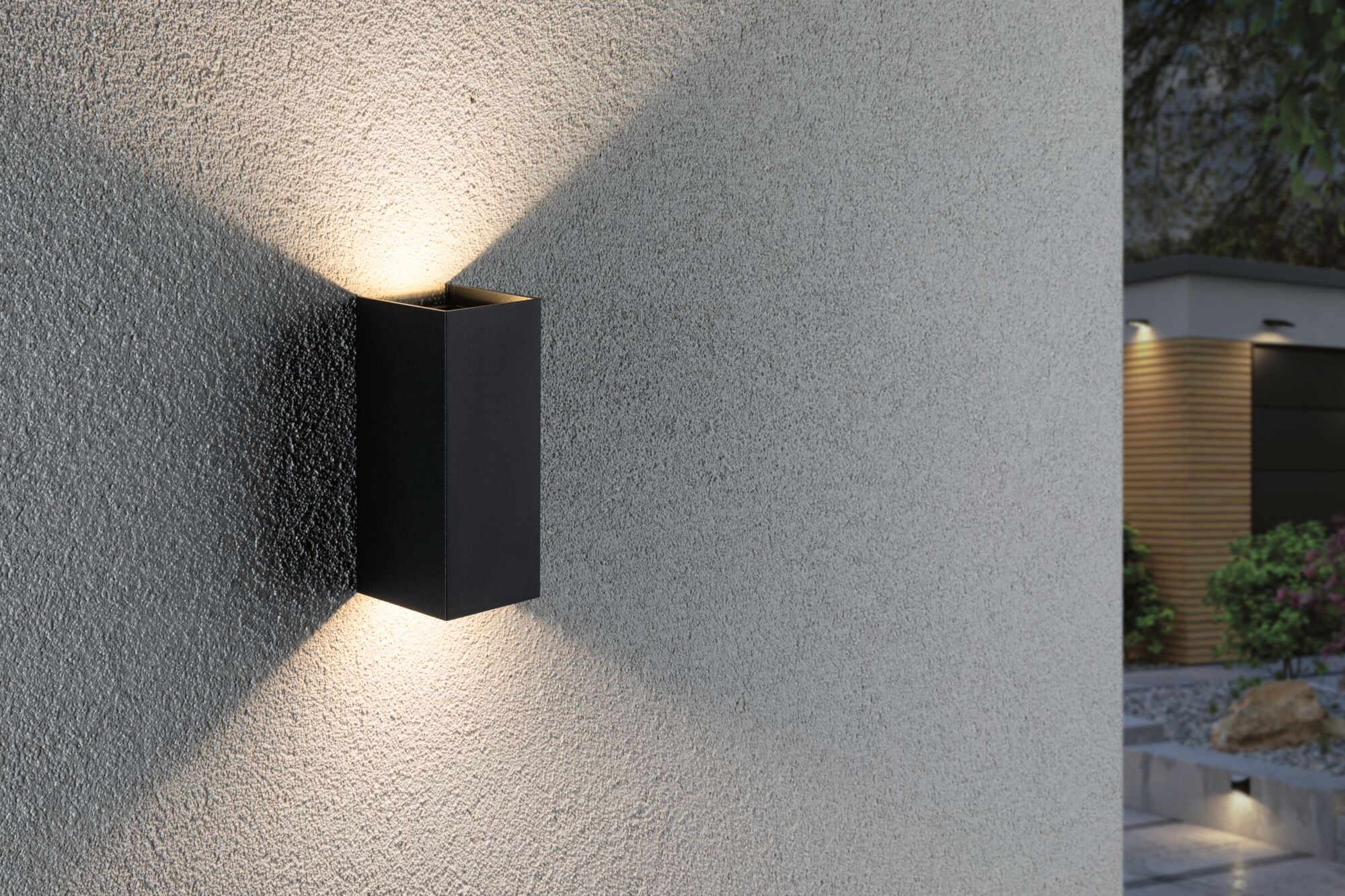 Schwarzer Wandstrahler beleuchtet strukturierte Wand mit Lichtkegeln.
