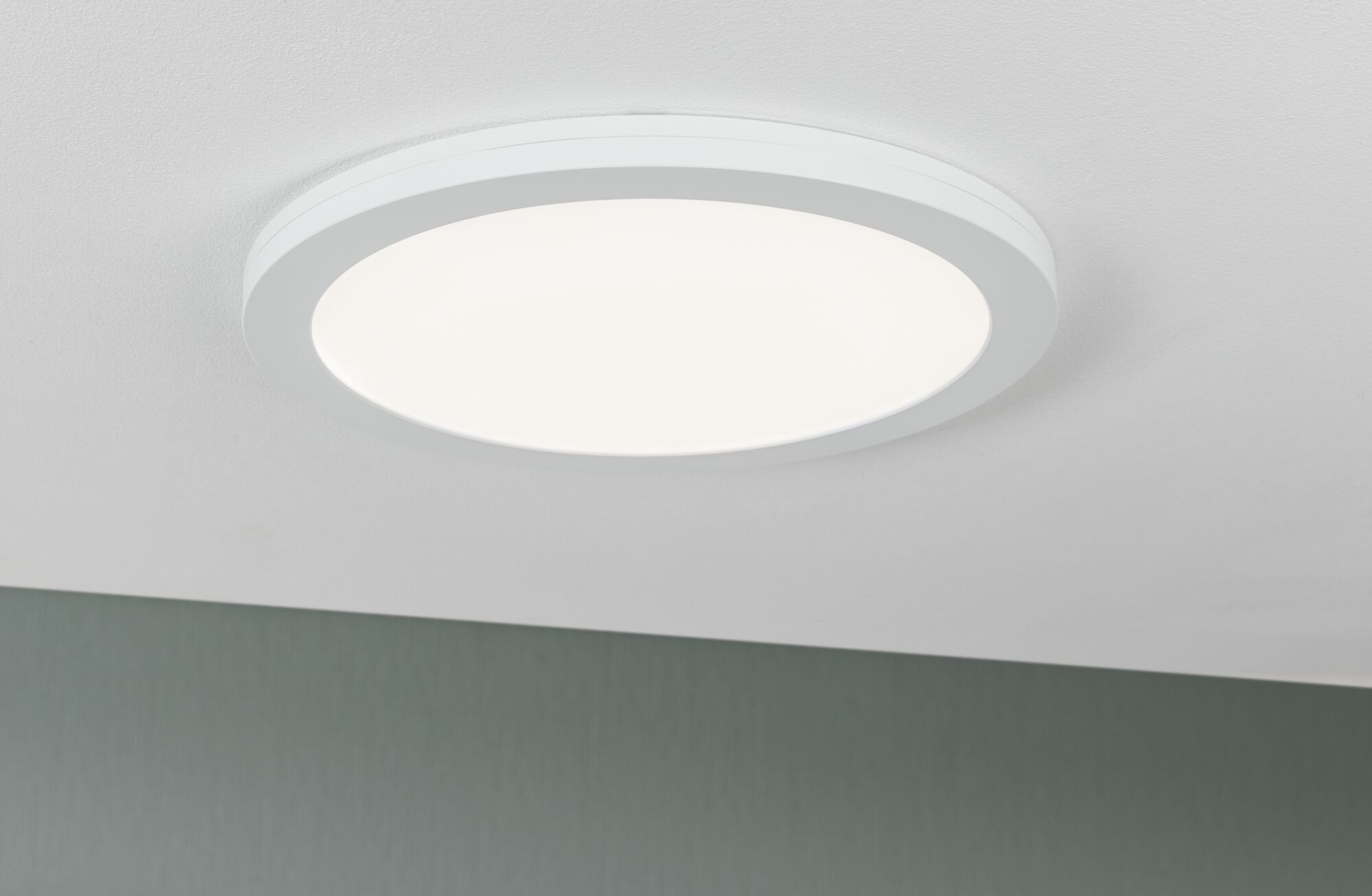 Eine weiße Deckenleuchte mit rundem, hellem Licht auf einer weißen Decke.