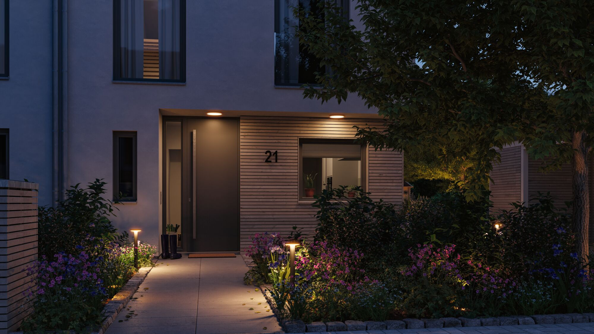 Ein modernes Haus mit Beleuchtung im Garten bei Nacht.