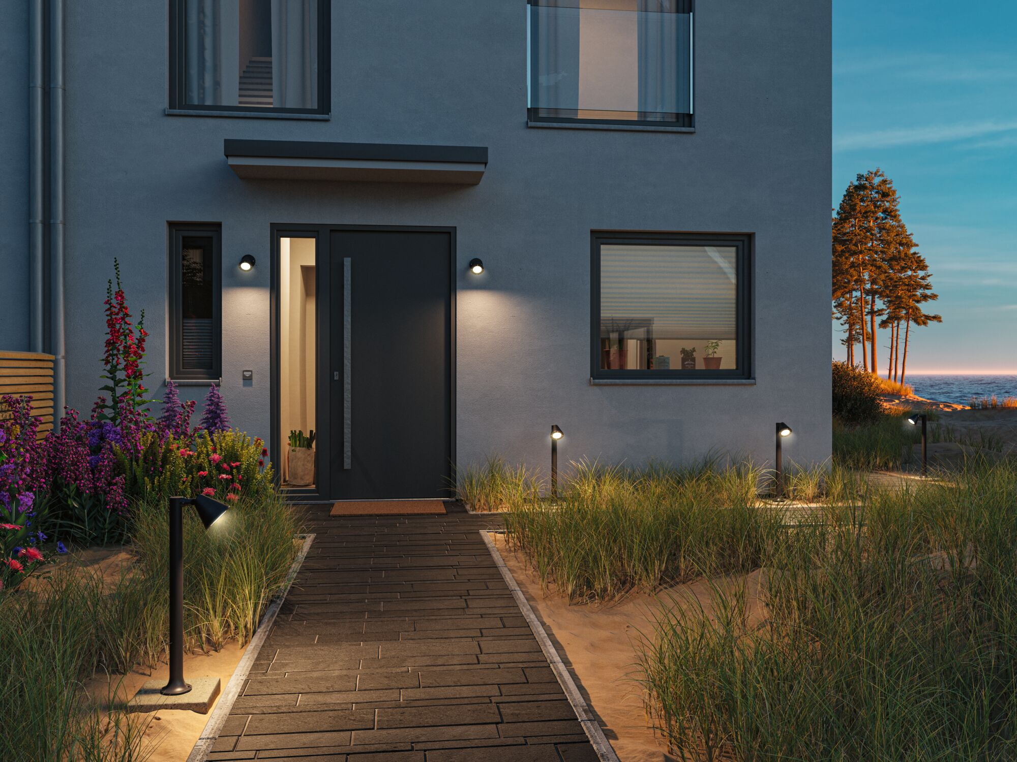 Dom ze ścieżką z płyt, kwiatami i trawą plażową w wieczornym świetle.