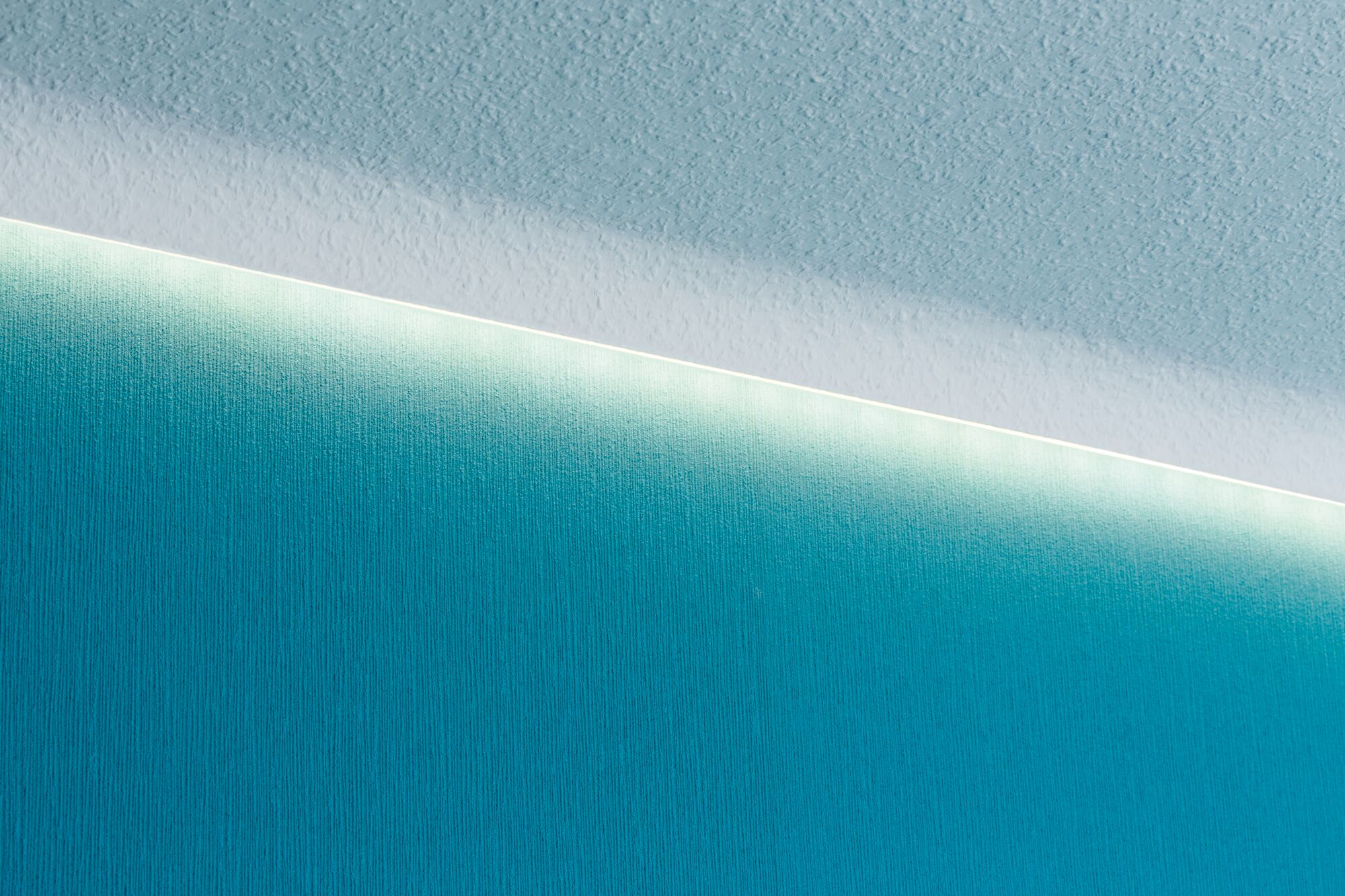 Niebieska ściana i biały sufit z paskiem LED pomiędzy nimi.