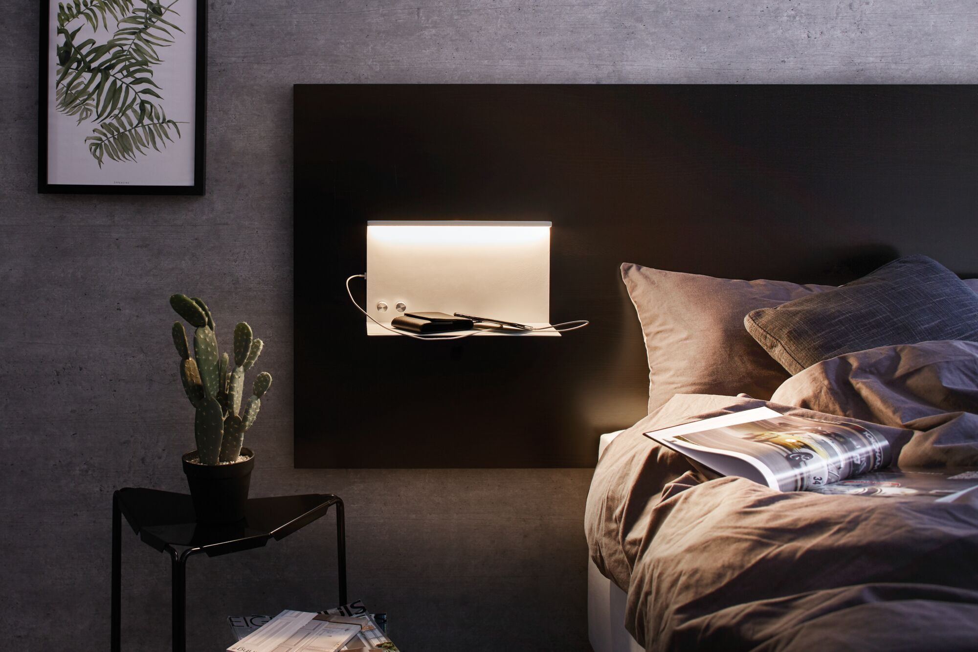 Nachttischansicht: Kaktus, gerahmte Pflanze, modernes Kopfteil mit Regal, Lampe, Geldbörse, Handy und Bett.