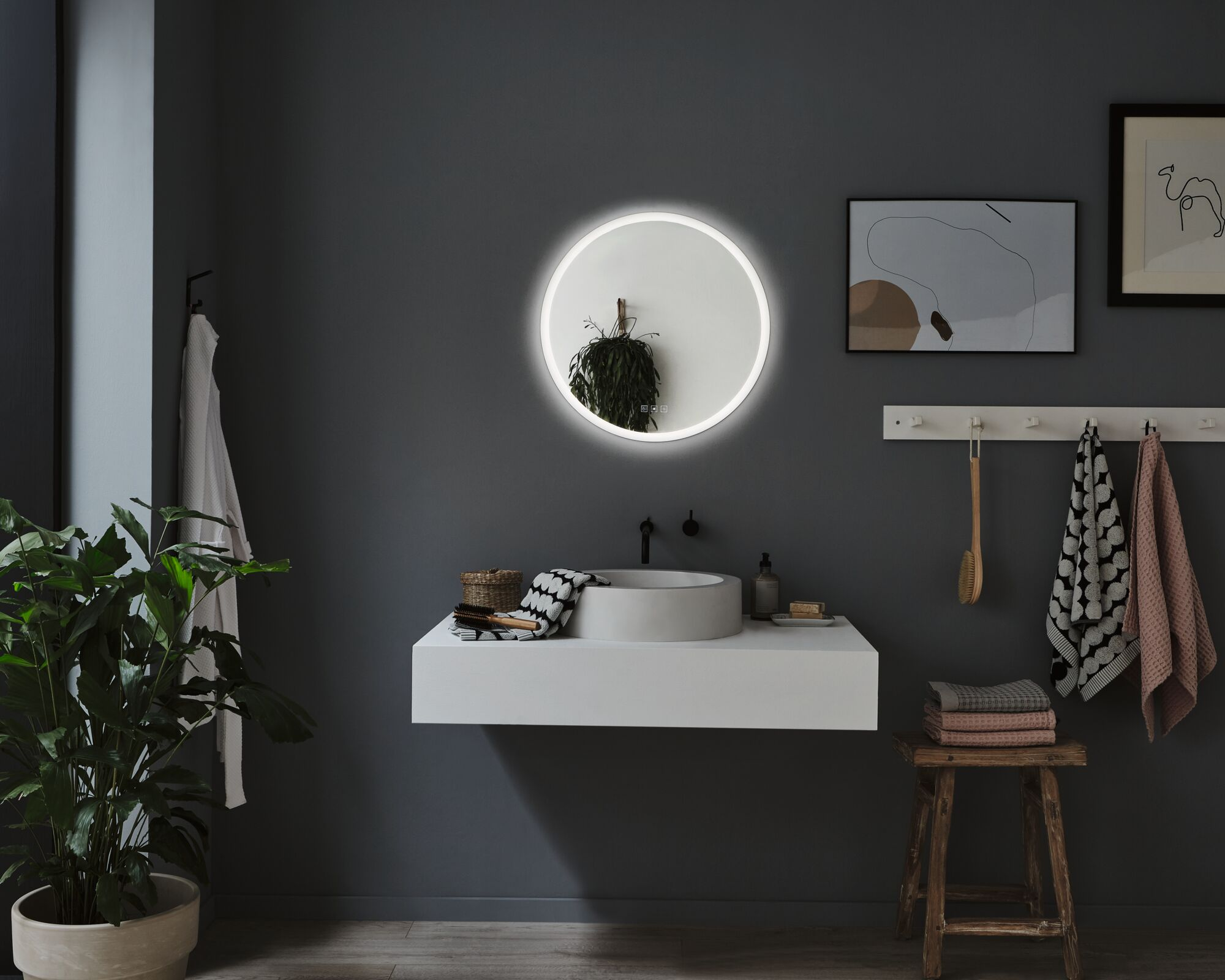 Salle de bain moderne avec vanité, miroir, plantes et serviettes.