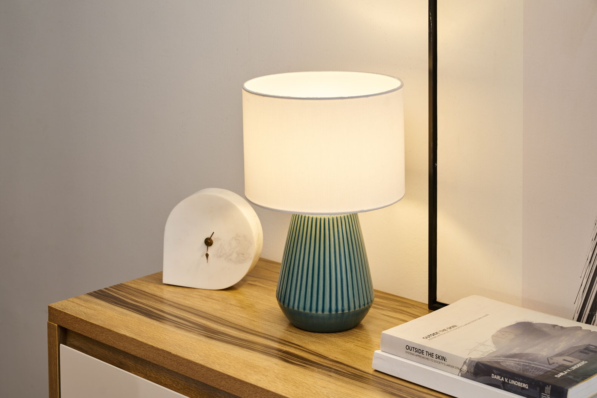 Stolik nocny z lampą, ozdobą i książkami.