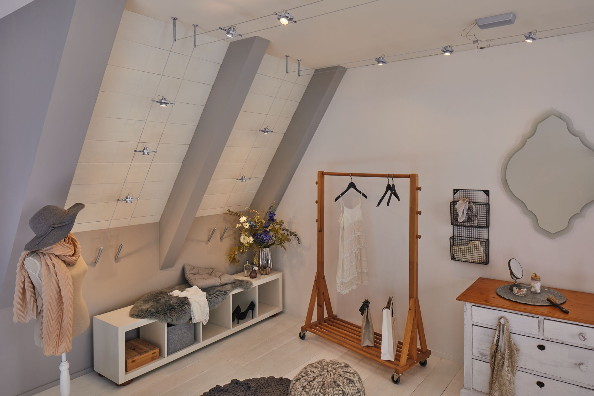 Un dressing avec portant, commode et miroir. Un mannequin porte un chapeau.