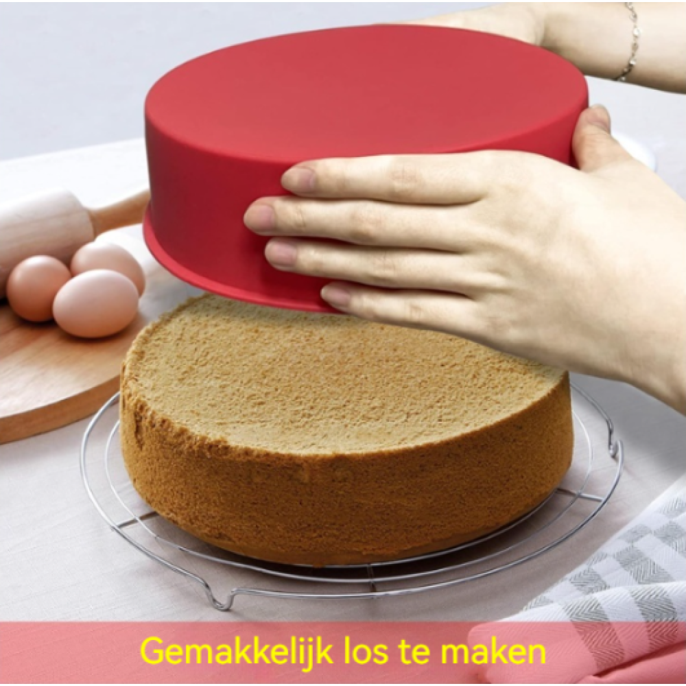 Rote Kuchenform wird von einem Kuchen abgehoben. Eier und Nudelholz im Hintergrund.