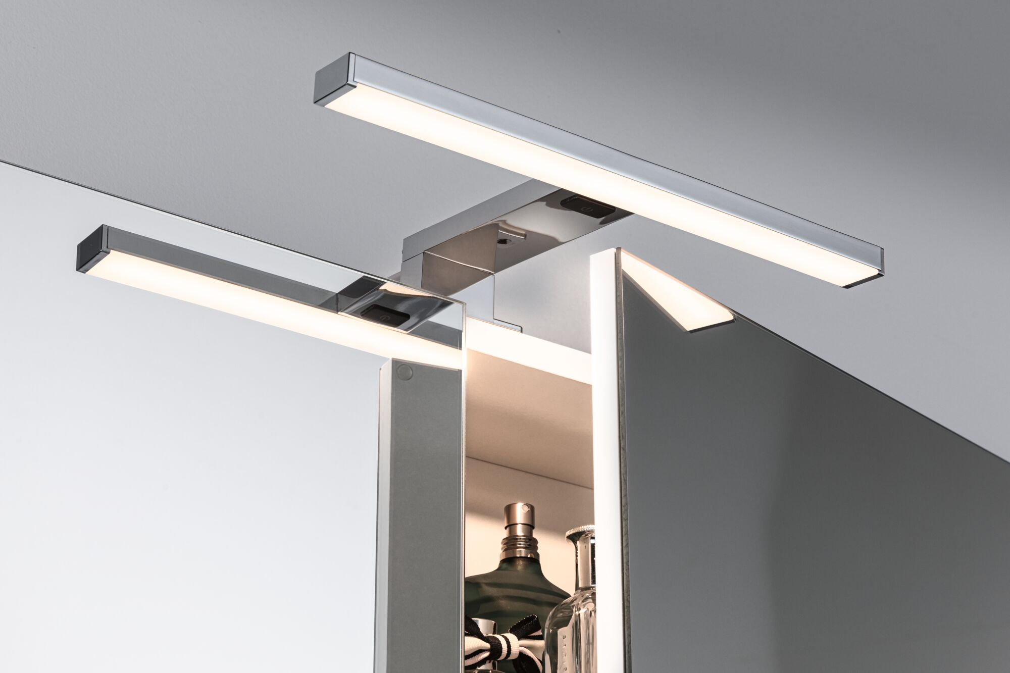 Luci LED moderne a plafone sopra un armadietto aperto con bottiglie di profumo.