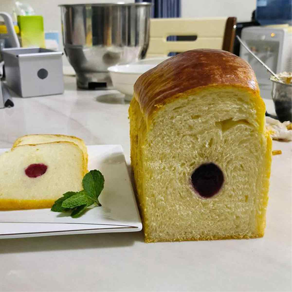 Ein Laib Brot mit einer Füllung in der Mitte, aufgeschnitten auf einem Teller mit Minze.