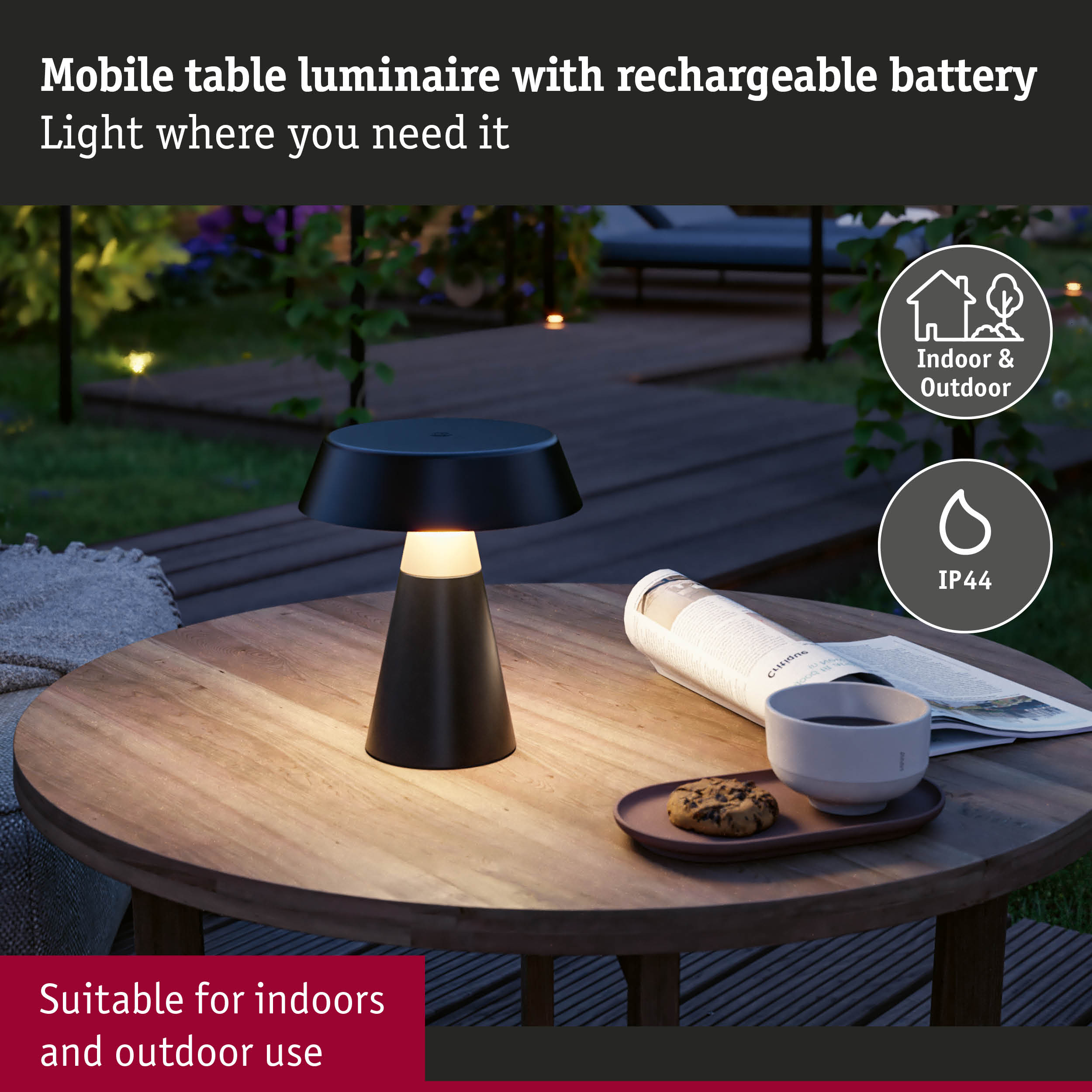 Czarna lampa stołowa na drewnianym stole z gazetą, filiżanką i ciasteczkiem na zewnątrz.