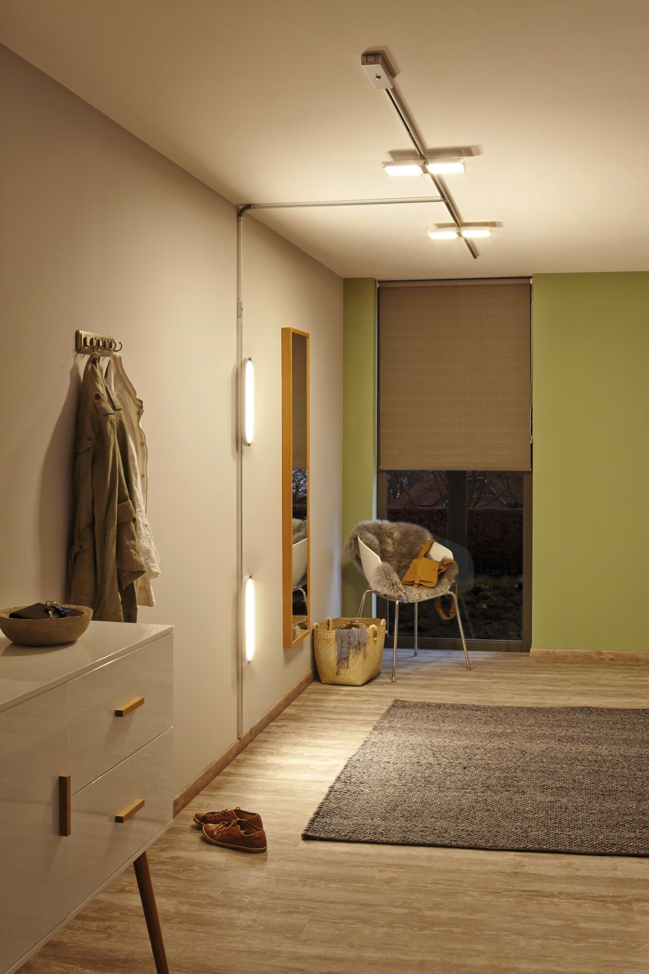 Ein Flur mit Kommode, Spiegel, Stuhl, Teppich und Garderobe.