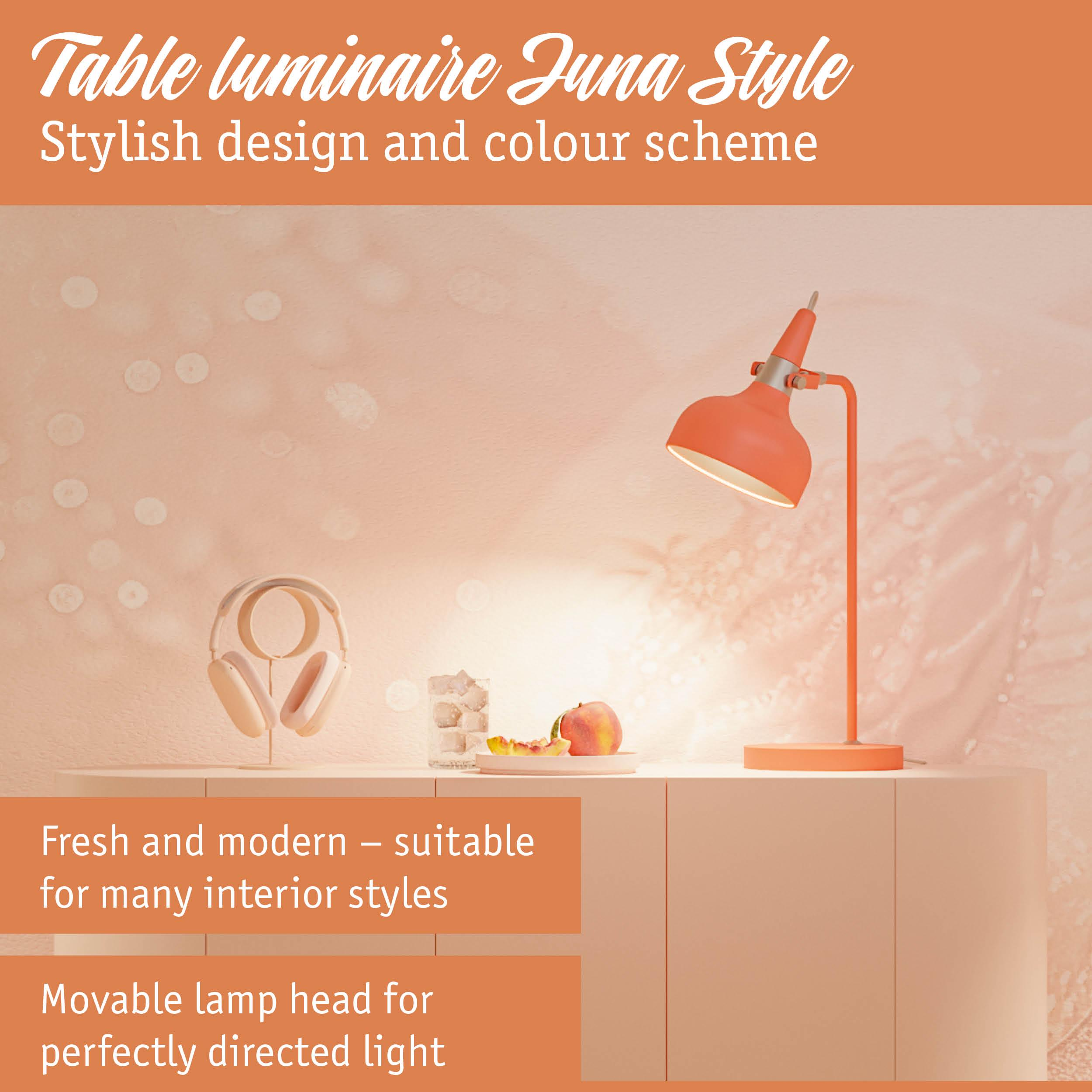 Pomarańczowa lampa biurkowa stoi obok słuchawek i owoców.