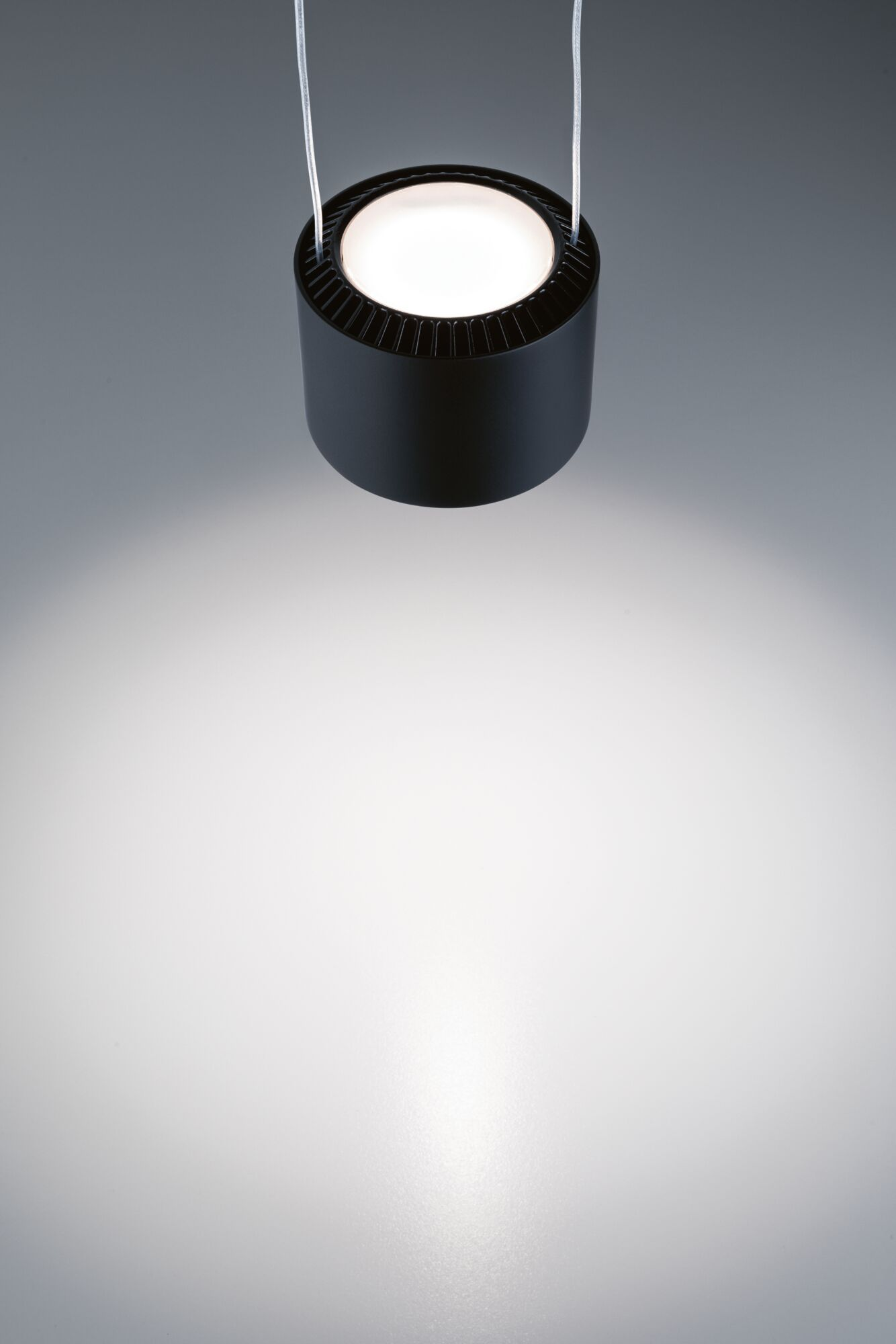 Eine schwarze Pendelleuchte mit einem hellen Lichtstrahl nach unten.