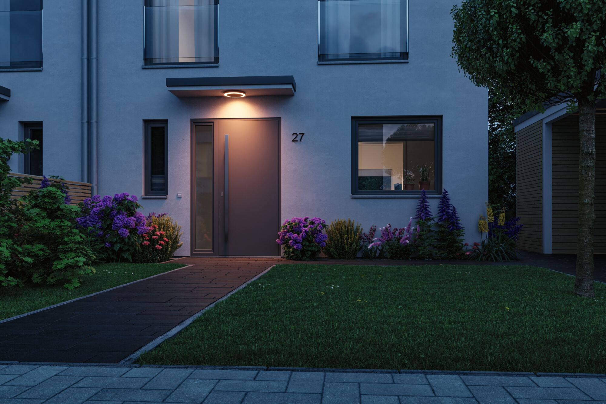 Ein modernes Haus mit Tür, Fenster, Blumen und Rasen bei Nacht.