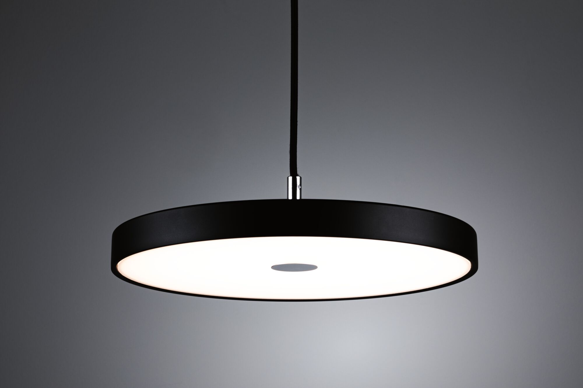 Schwarze Hängeleuchte mit runder, weißer Lichtfläche und grauem Zentrum.