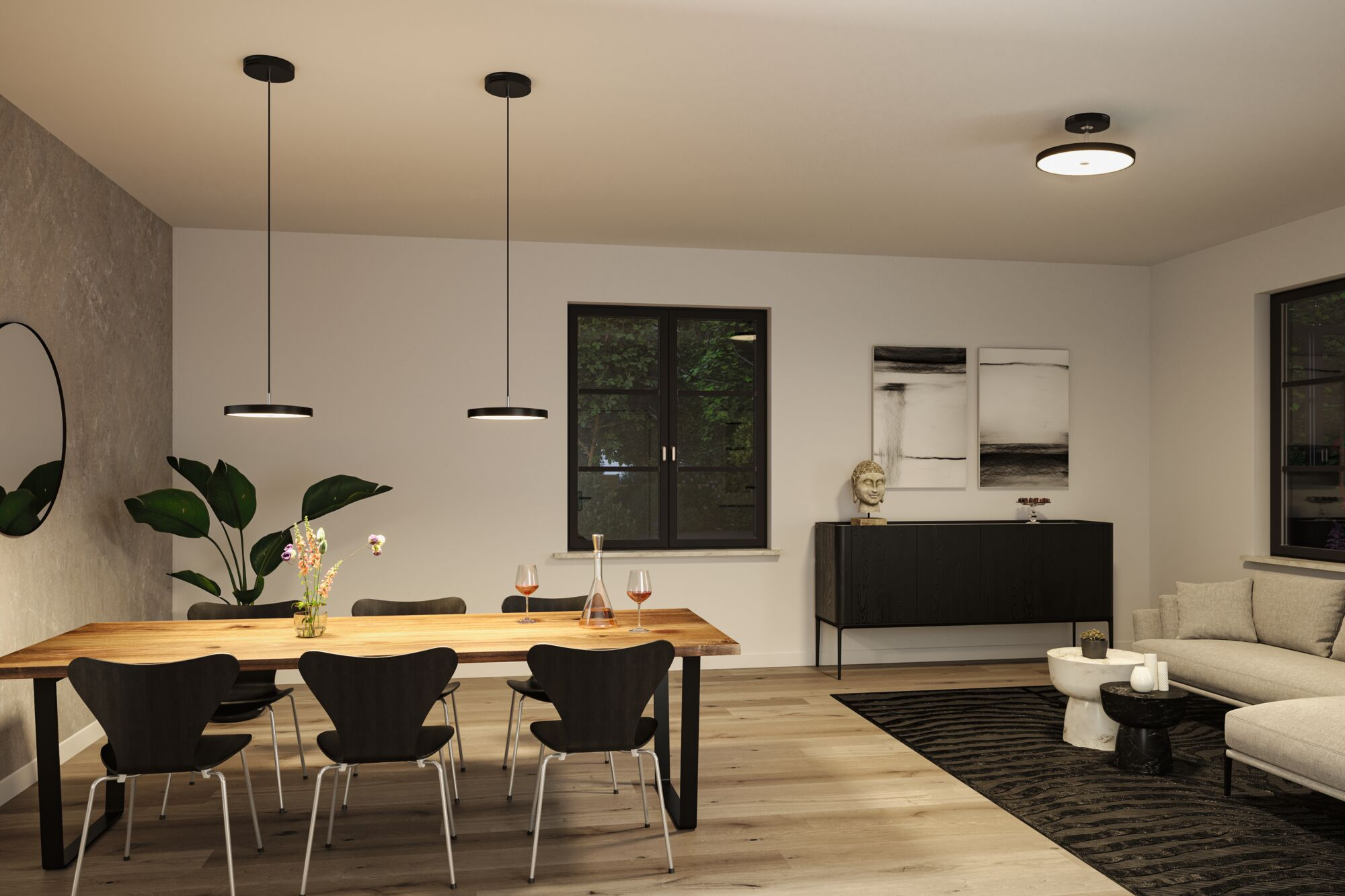 Ein Esszimmer mit Holztisch, schwarzen Stühlen, Pflanzen und einem Wohnbereich.