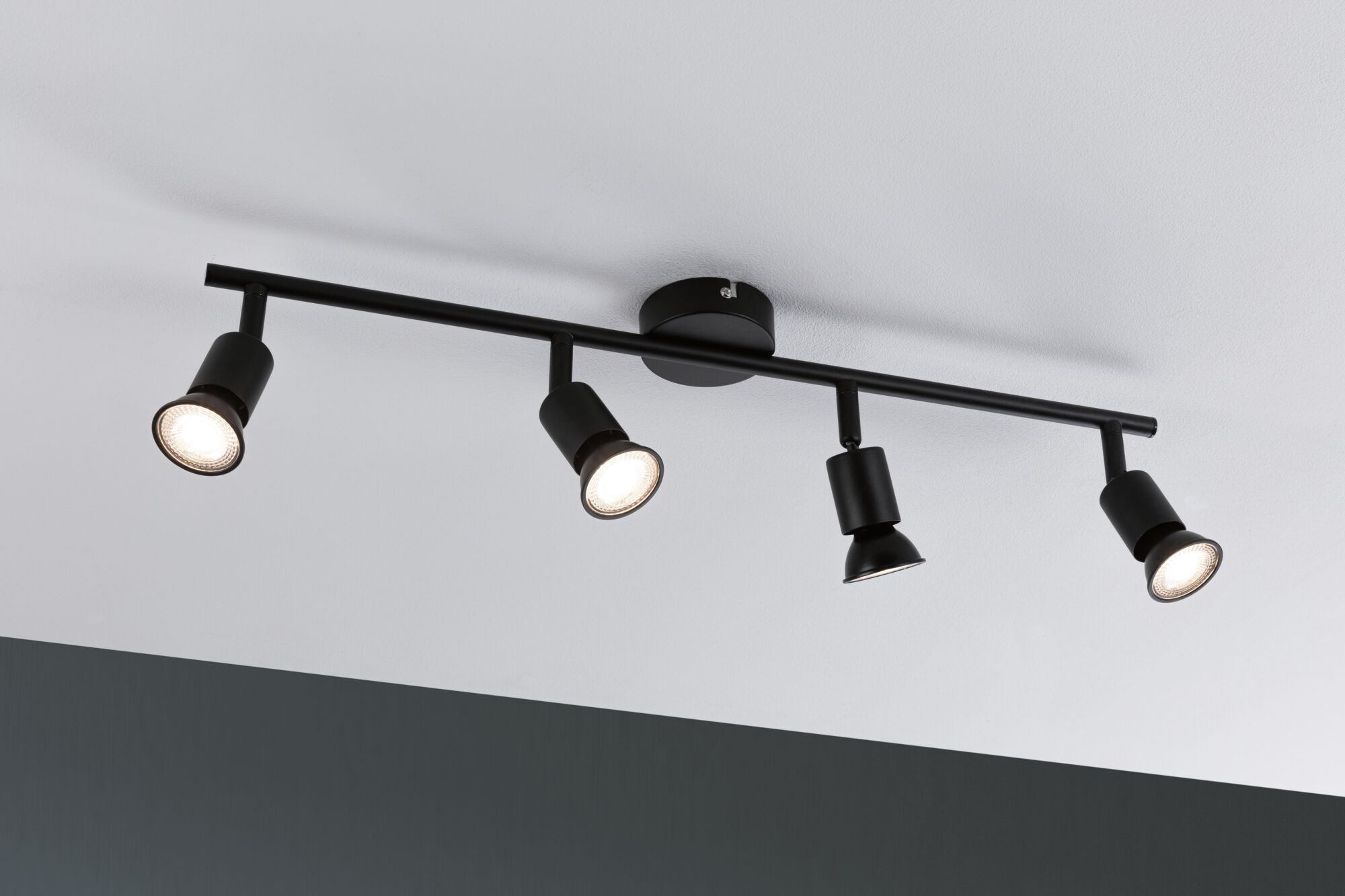 Czarna lampa sufitowa szynowa z czterema regulowanymi spotami.
