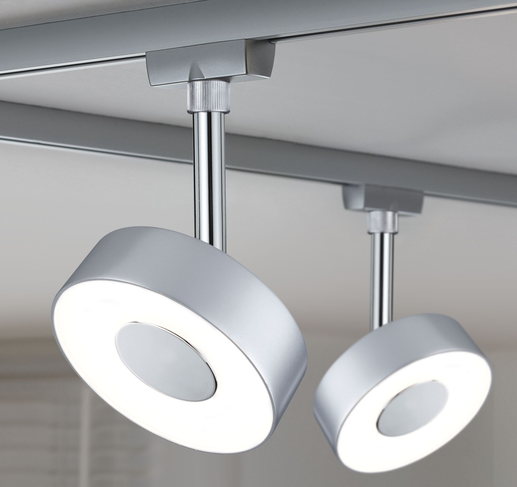 Zwei moderne, runde Deckenleuchten aus Metall mit weißem Licht auf einer Schiene.