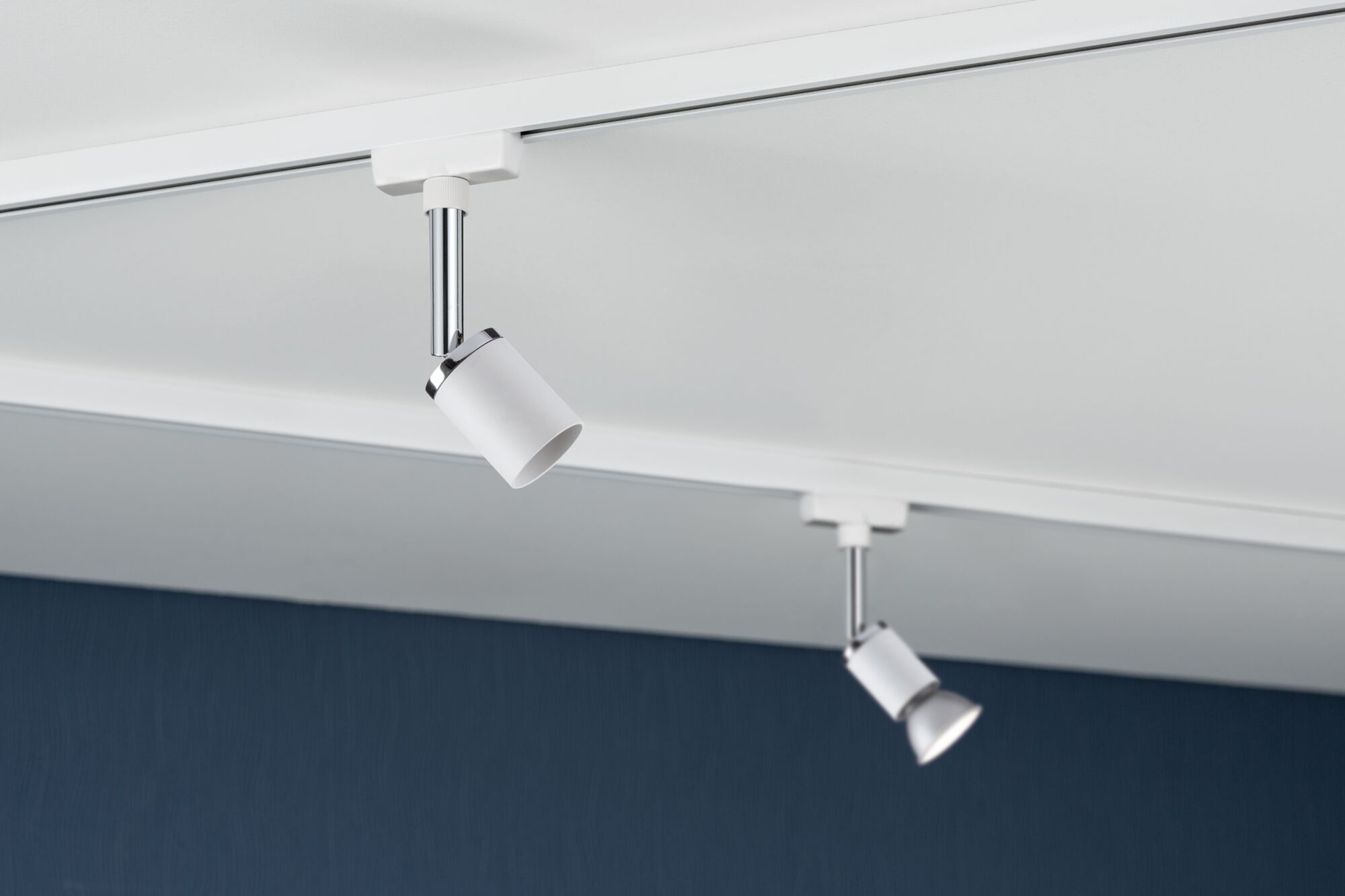 Due faretti su binario bianchi con accenti cromati su soffitto bianco.