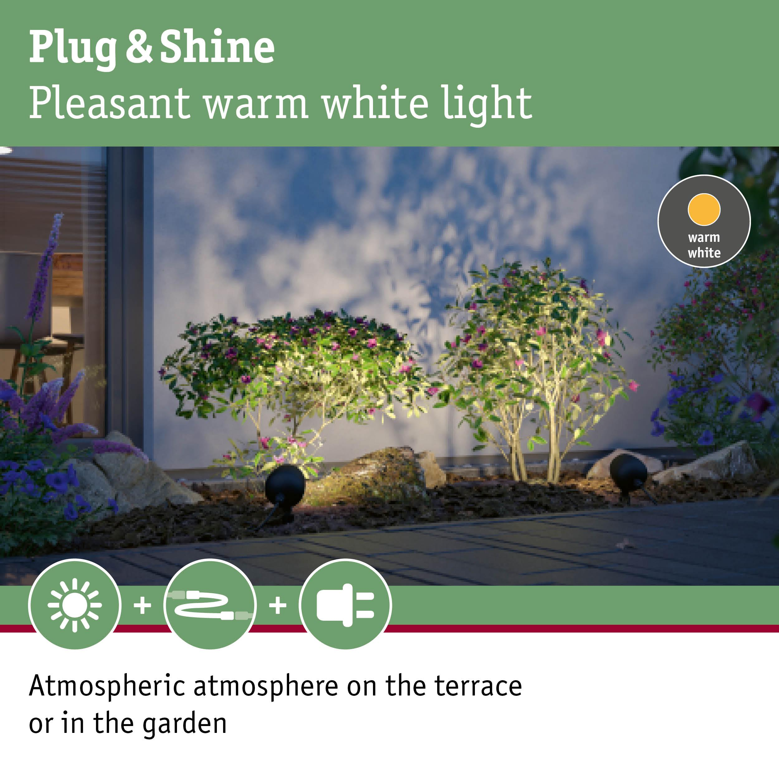 Beleuchtete Büsche und Blumen auf einer Terrasse mit warmweißem Licht.