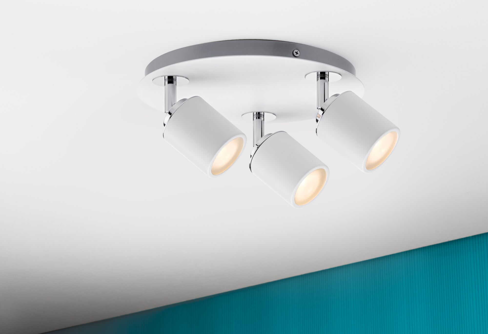 Biała lampa sufitowa z trzema regulowanymi reflektorami i chromowanymi detalami.