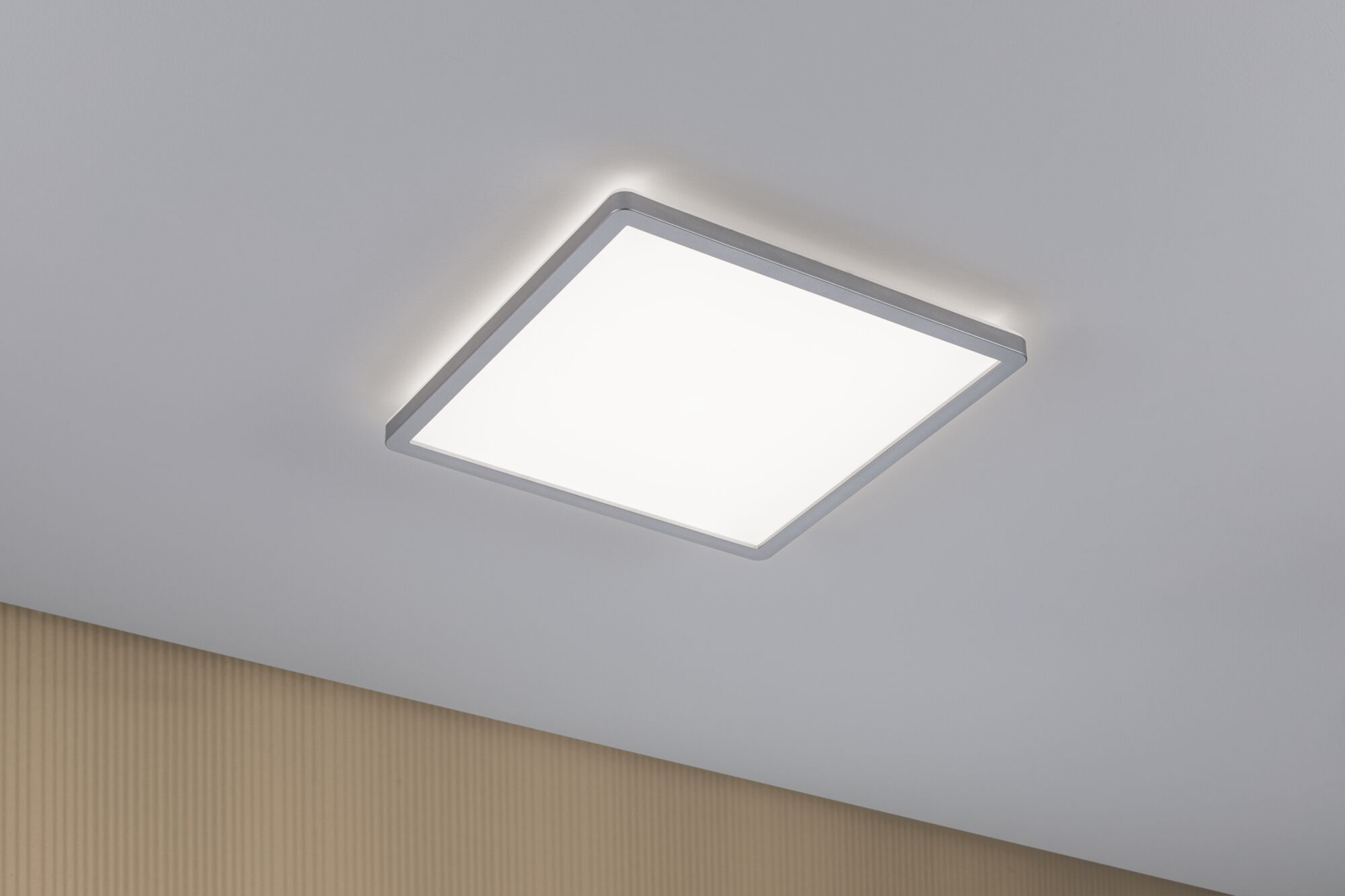 Prostokątna lampa sufitowa ze srebrną ramą jasno świeci.