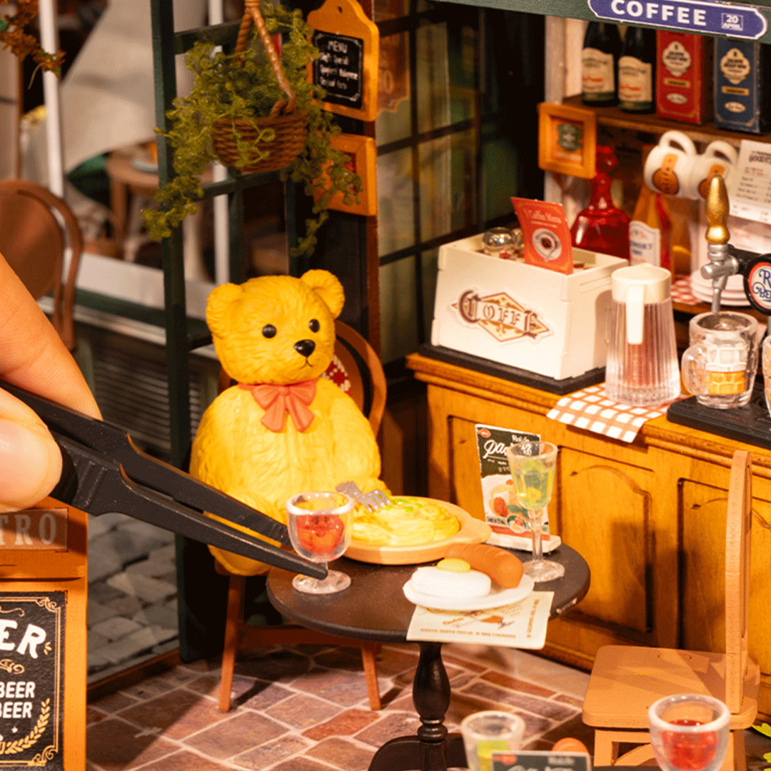 Teddybär sitzt im Café vor einem Tisch mit Essen und Getränken.