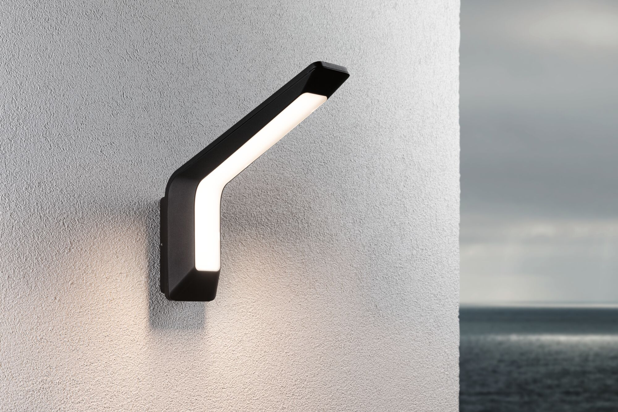 Nowoczesna czarna lampa ścienna emituje czyste światło na szarej ścianie.