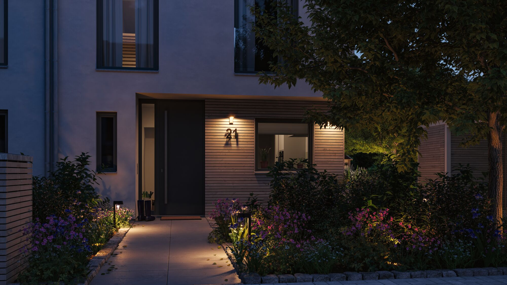 Nowoczesny dom z drewnianą fasadą i rabatką nocą.