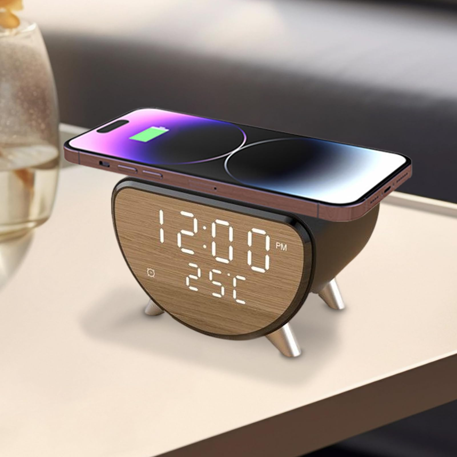 Ein Smartphone mit grünem Akkusymbol auf einem Holz-Wecker mit digitaler Anzeige.