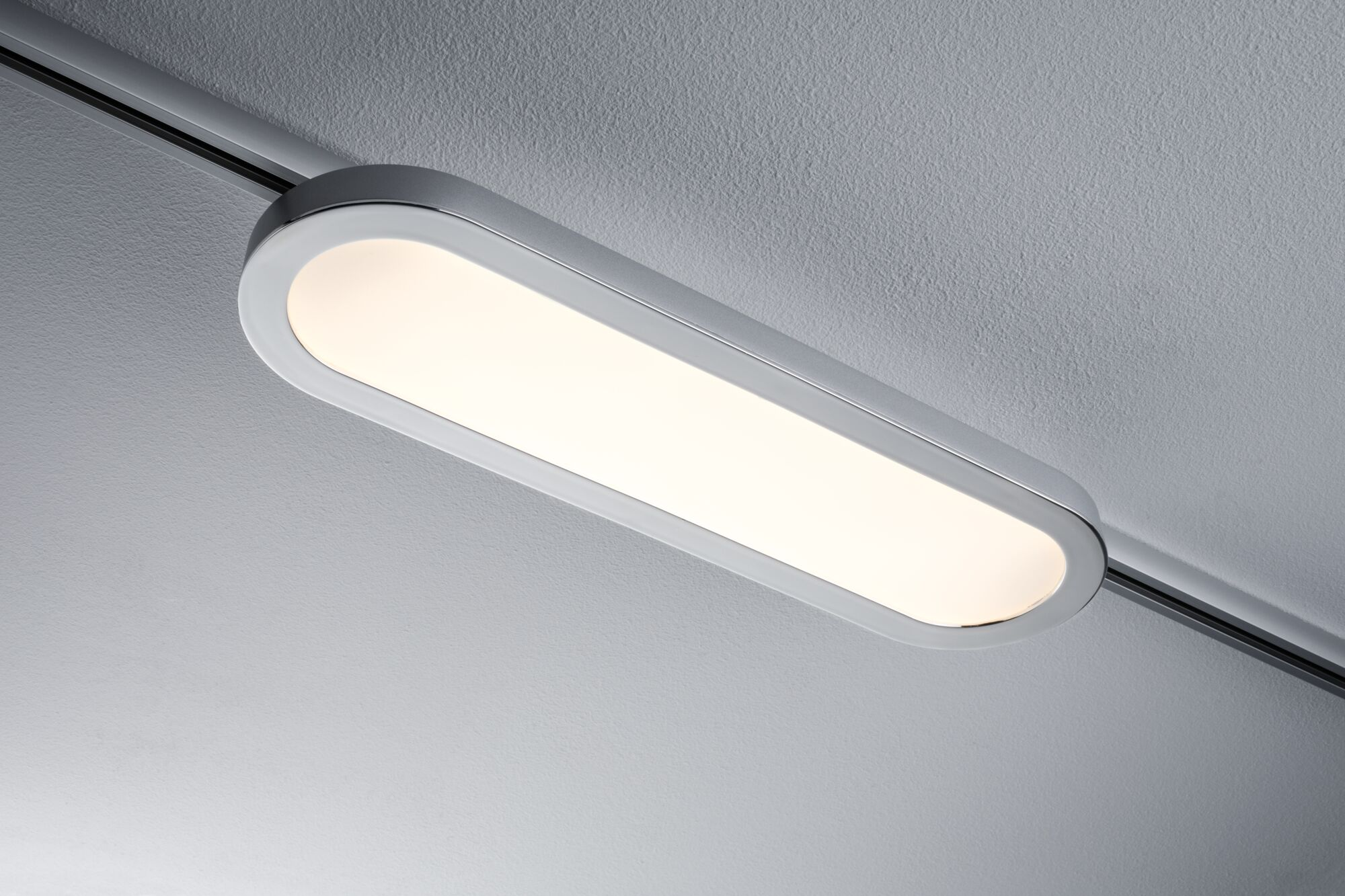 Un moderno apparecchio di illuminazione oblungo con luce bianca su un soffitto grigio.