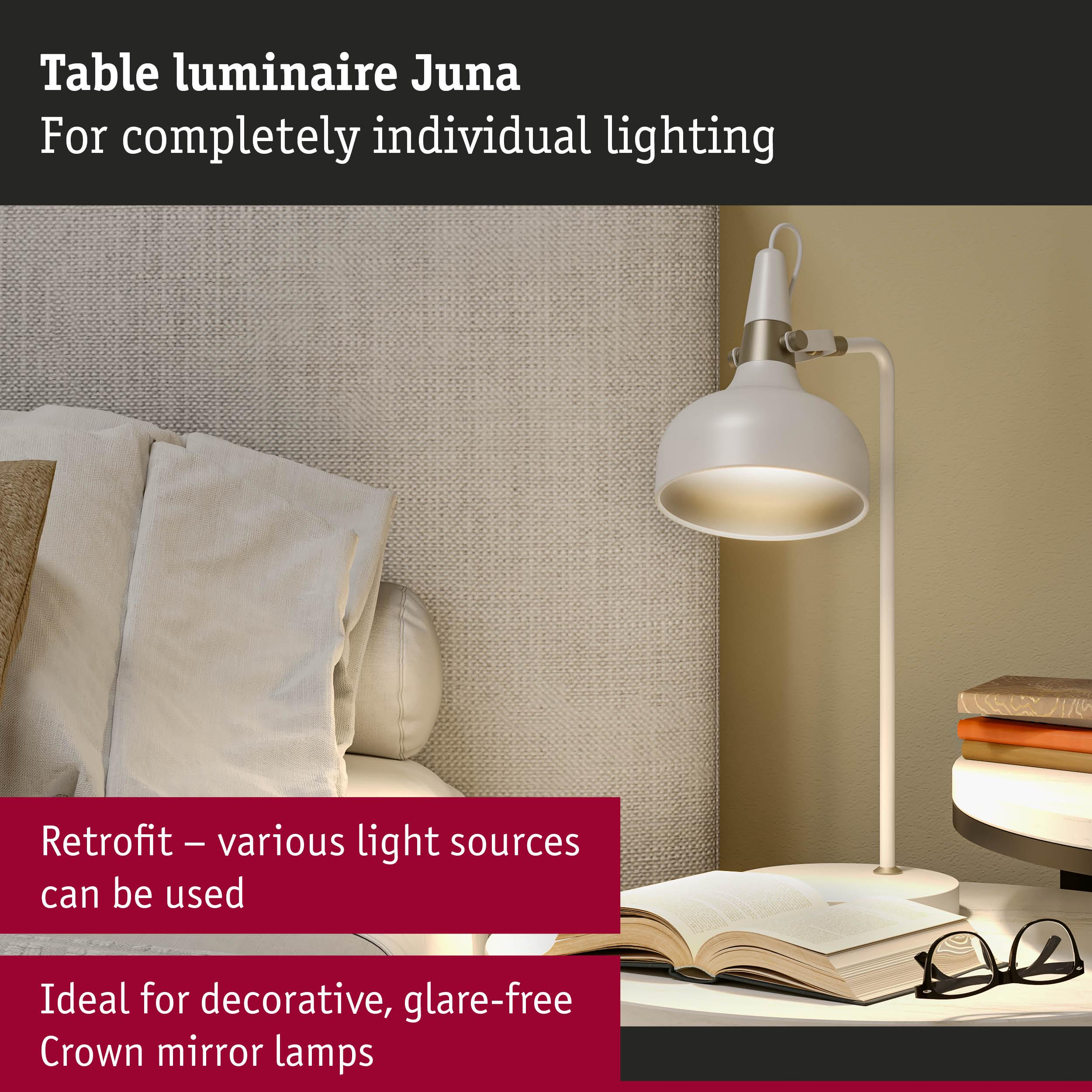 Biała lampa stołowa obok łóżka, z otwartą książką i okularami.