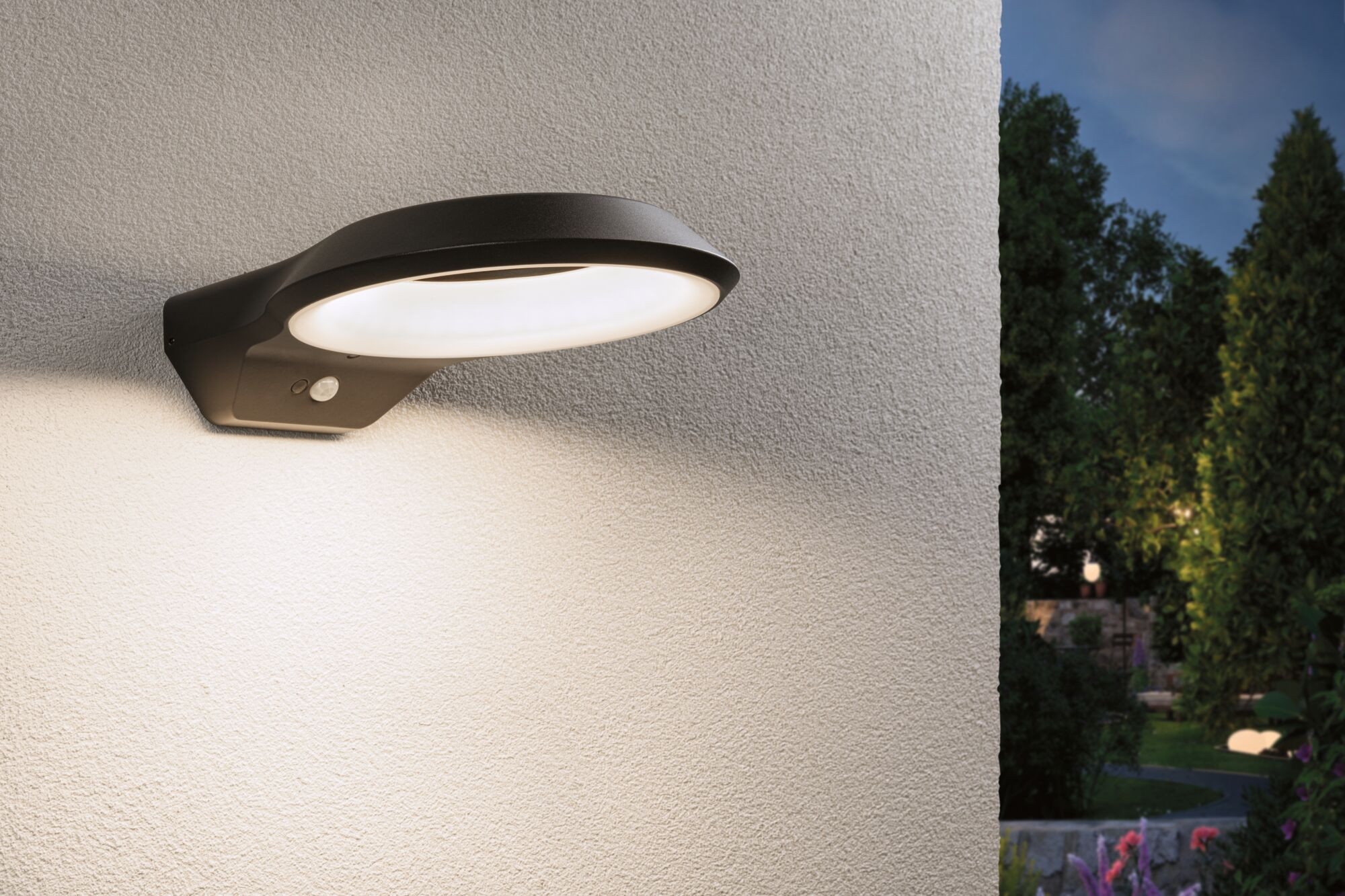 Nowoczesna lampa ścienna z czujnikiem ruchu oświetla ścianę domu nocą.